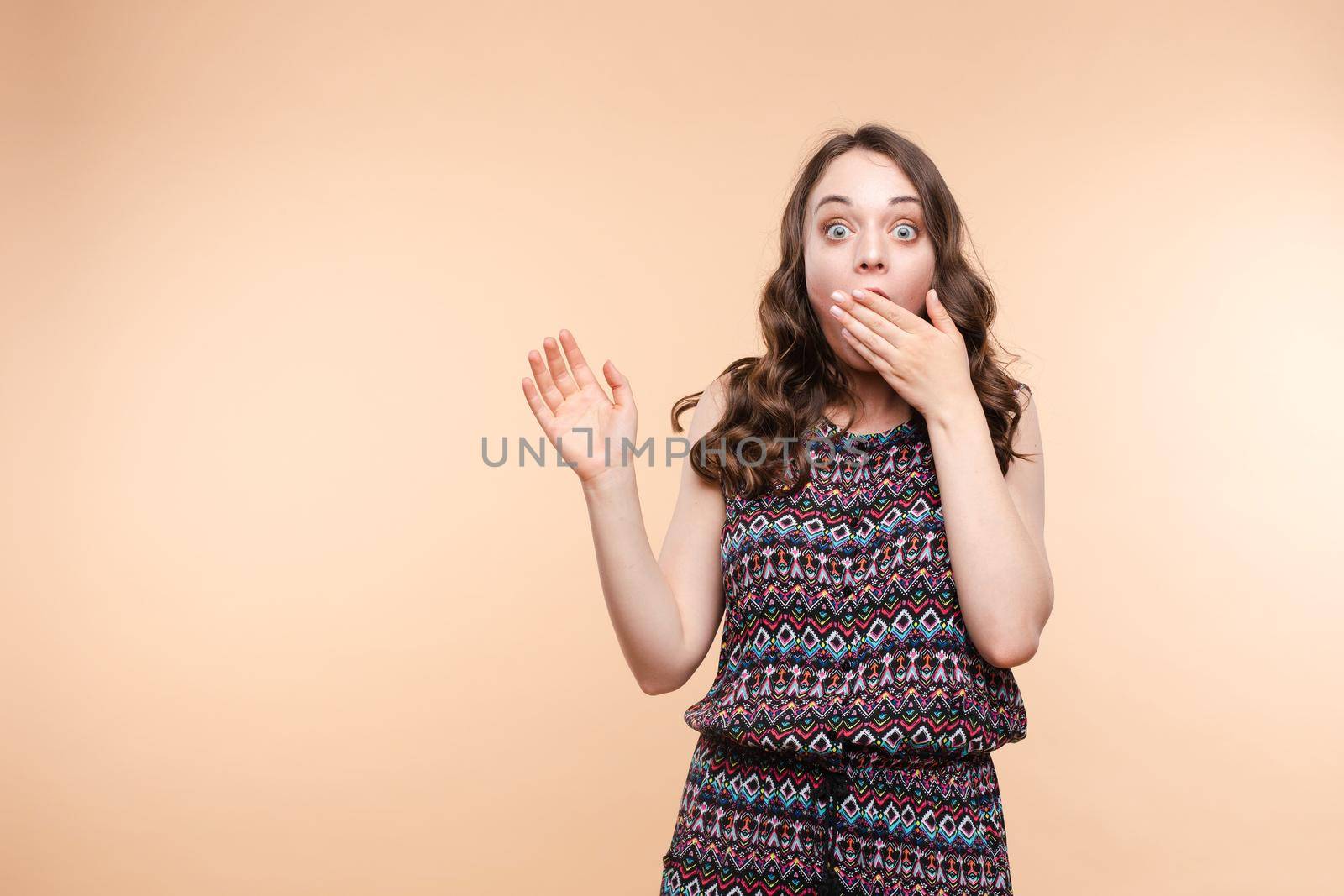 Waist up portrait of surprised beautiful girl with nice long hair, perfect makeup and fashion manicure. She is looking at camera with astonishment. Isolated on dark background