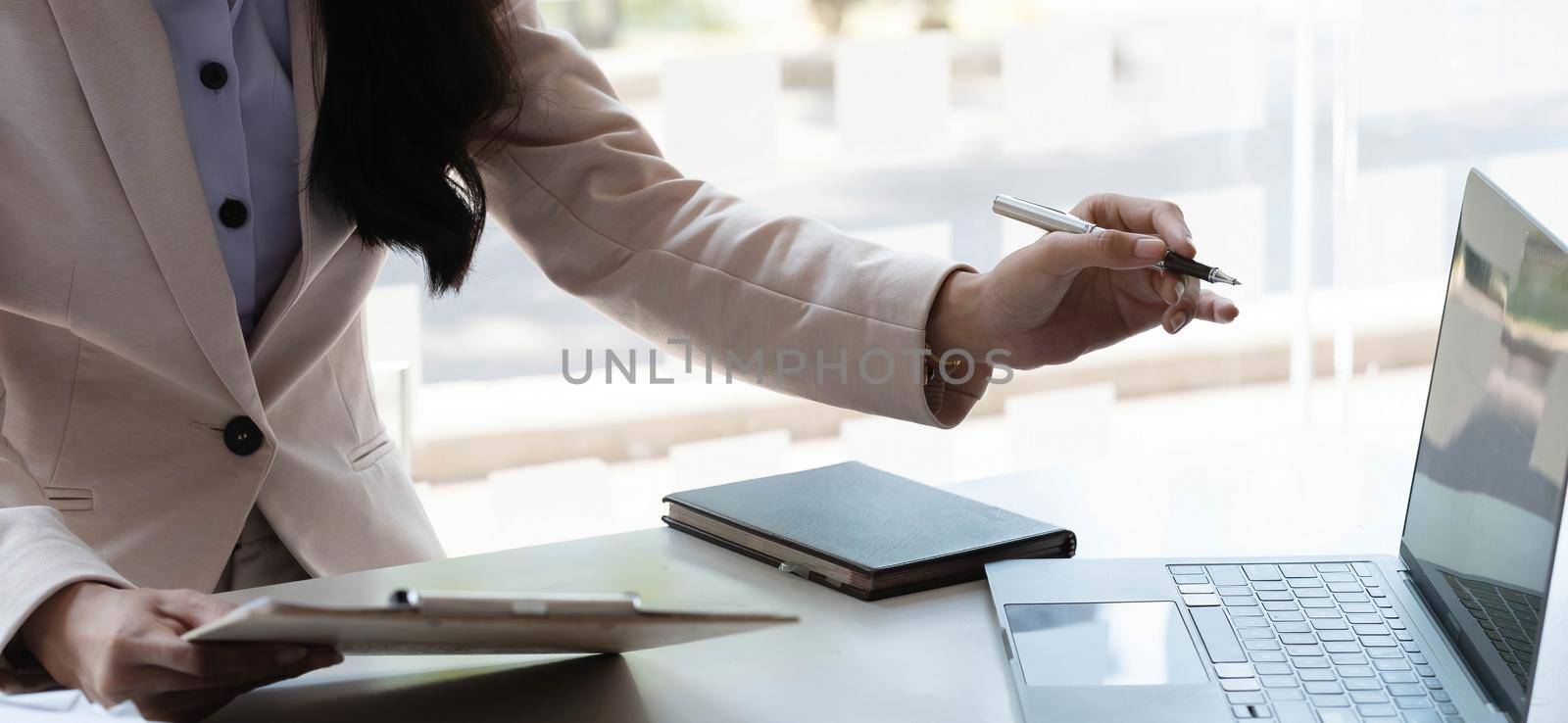 businesswoman working pointing laptop computer and discussing documents and idea. by wichayada