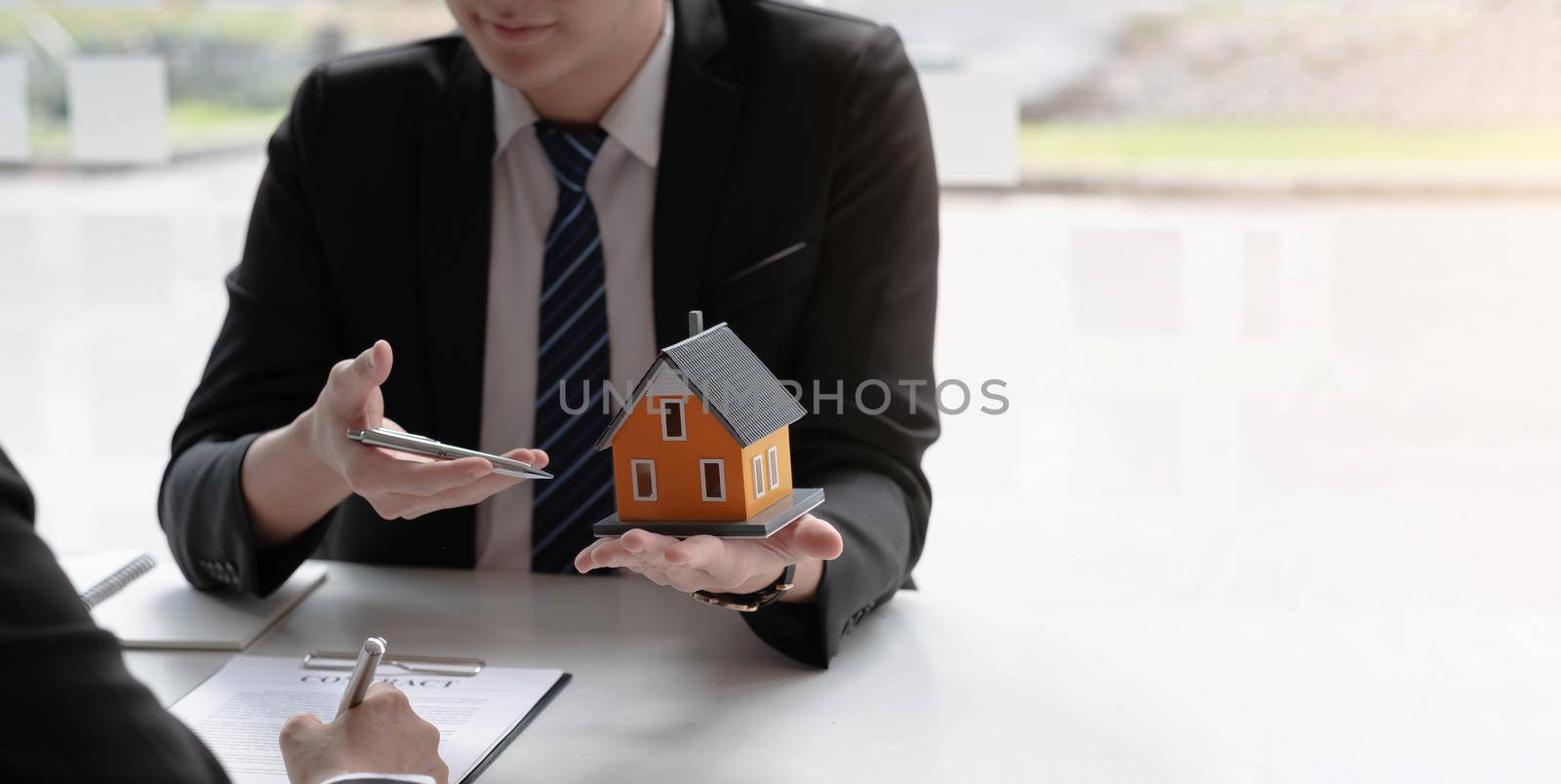 Real estate agent to buy house and land are delivering house to customer after agreeing to make a home purchase agreement. by wichayada