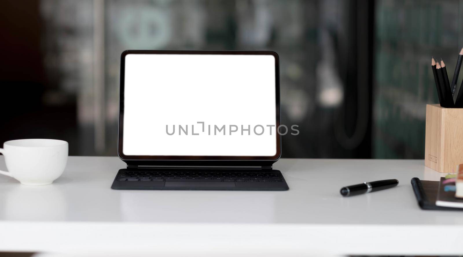 Side view of contemporary workplace with laptop computer, notebook, coffee cup and stationery on wooden table..