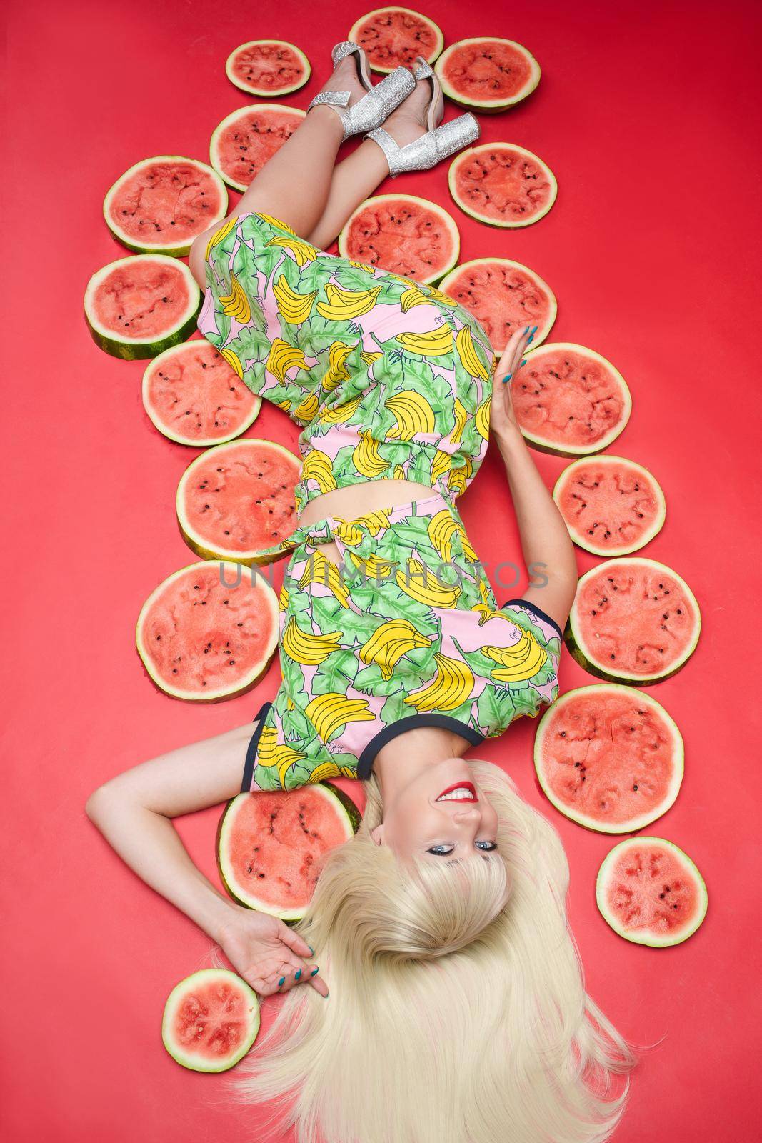 Sexy beautiful young woman lying on floor posing for photo shooting surrounded by watermelon by StudioLucky