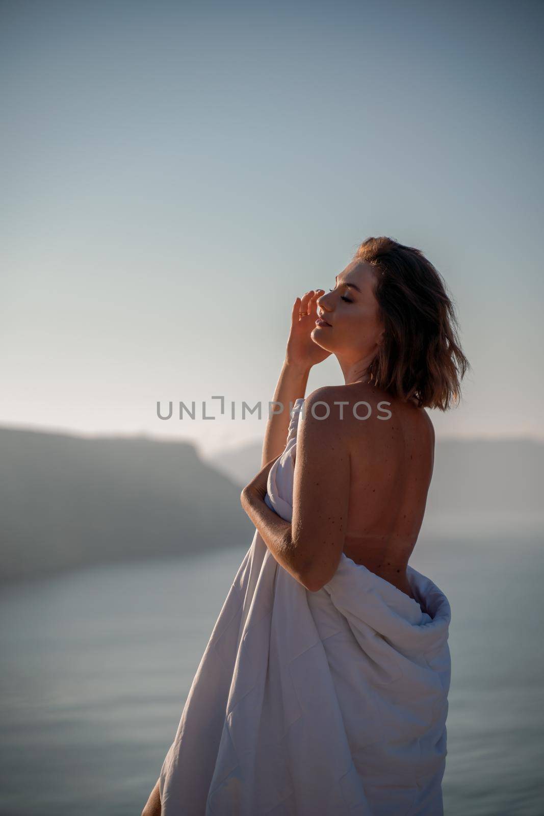 Woman wake up in bed wuth duvet and pillow over nature sea background outdoors. Back view. Good morning. Freedom concept. by Matiunina