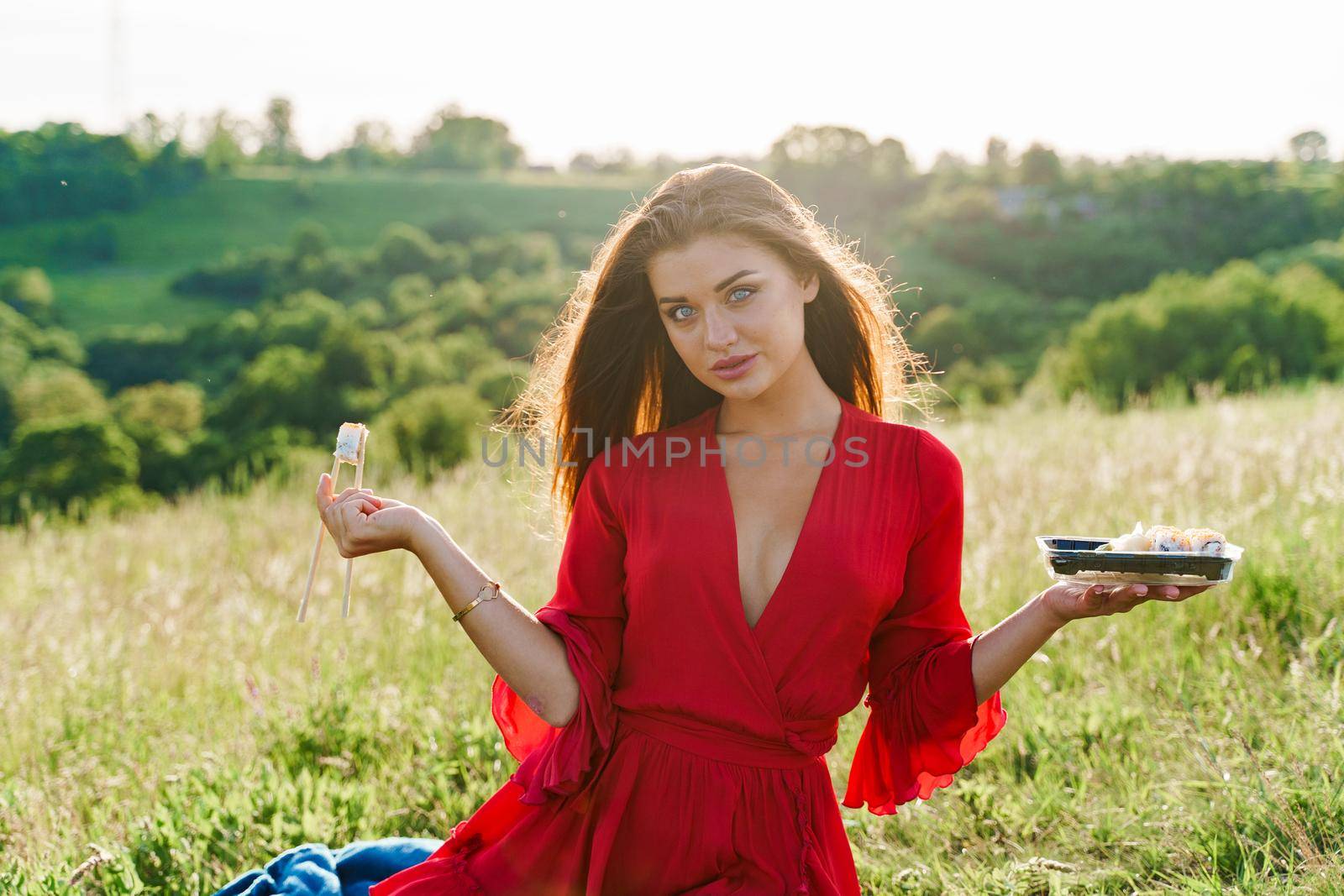 Sushi and sexy girl with blue eyes at picnic. Food delivery from japanese restaurant. Advert for social networks. Pretty girl with sushi set in 2 hand in the park.