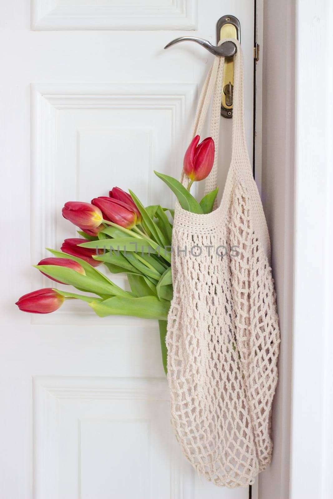A beautiful bouquet of tulips with a string bag. Banner for the Happy Easter holiday, Woman's Day Copy space. Flat lay, top view. Spring aestetic.