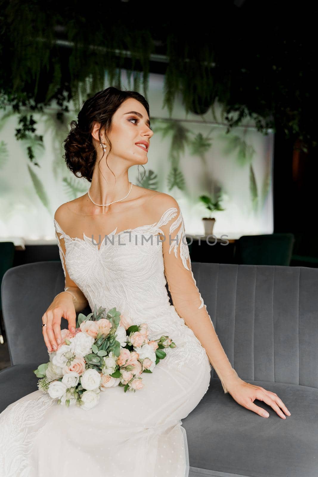 Bride in wedding dress and bridal veil seats on fashion chair in cafe. Advert for social networks for wedding agency and bridal salon.