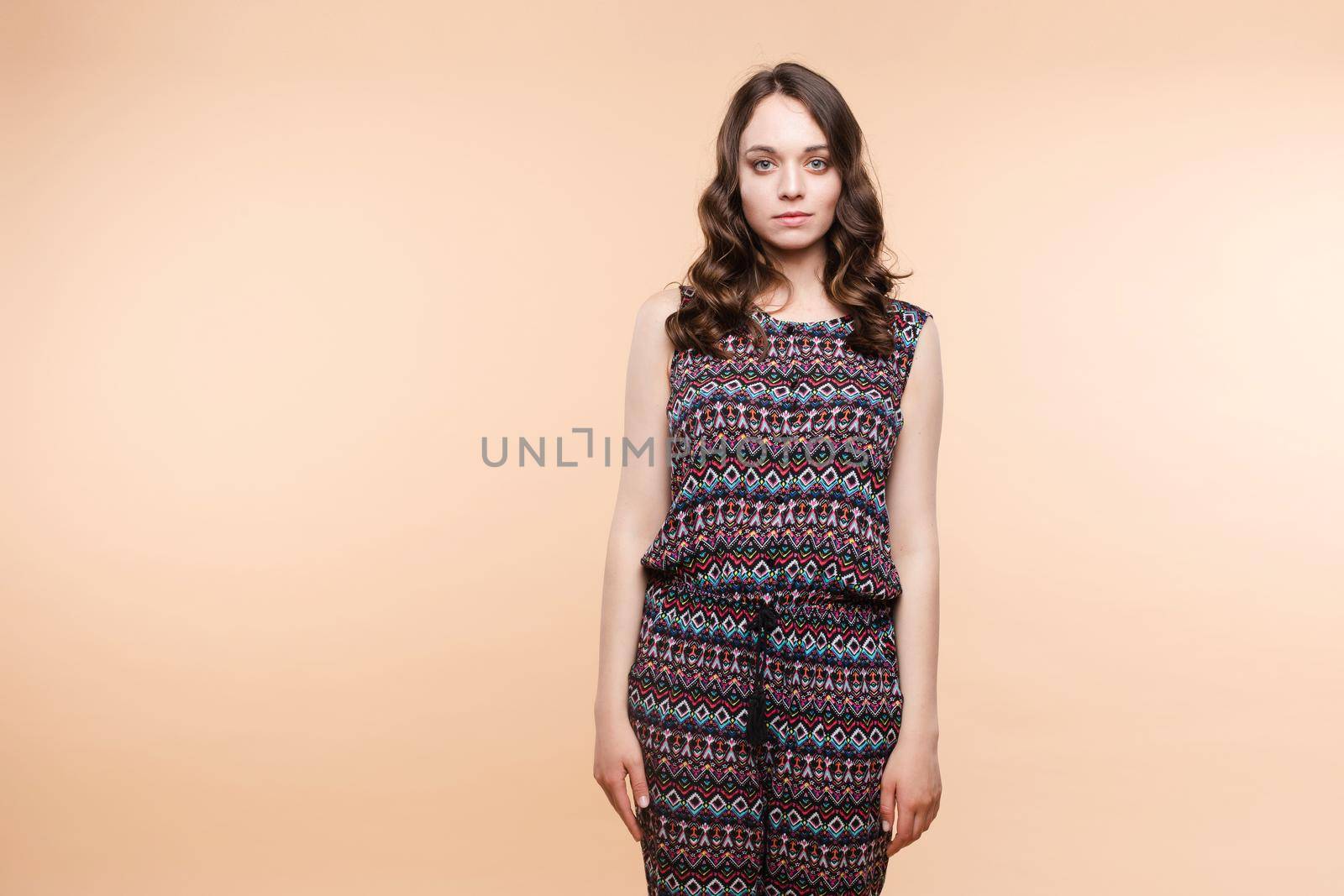 View from front of beautiful slim woman standing steady on frey isolated background. Young looking at camera, smiling and posing in studio.