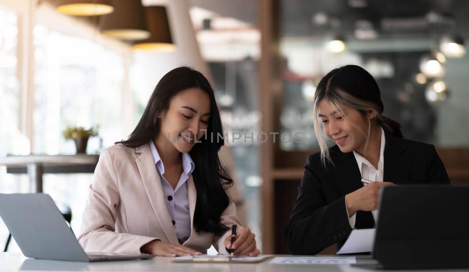 Two beautiful young asian businesswoman working together using digital tablet at office..