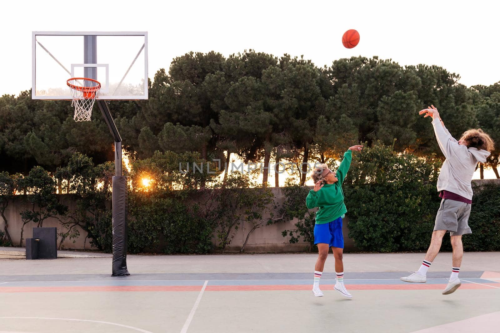 young latin woman playing basketball with a caucasian man on a city court, concept of urban sport in the street