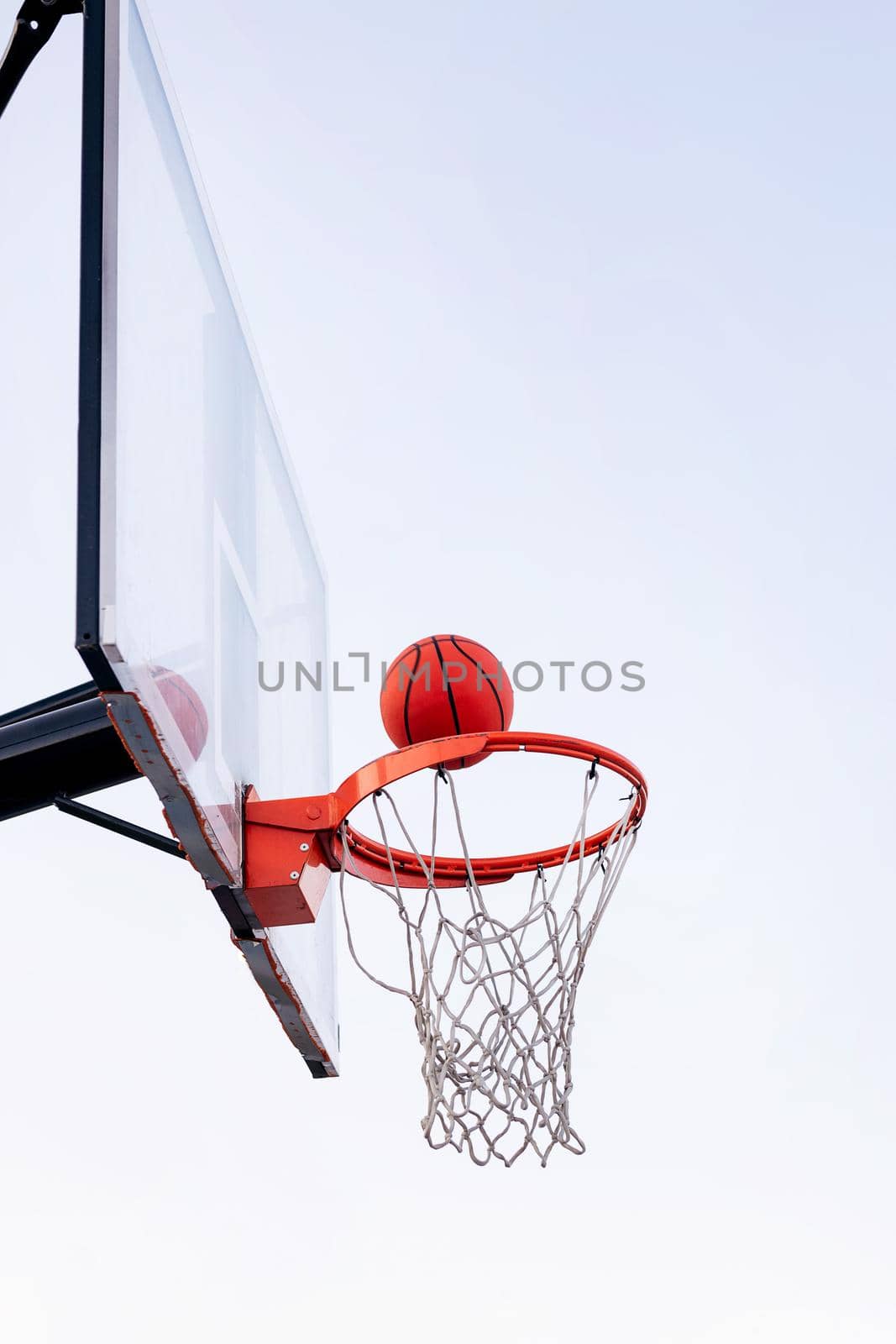 ball entering in a basketball hoop with the sky in the background, concept of urban sport outdoors, copy space for text