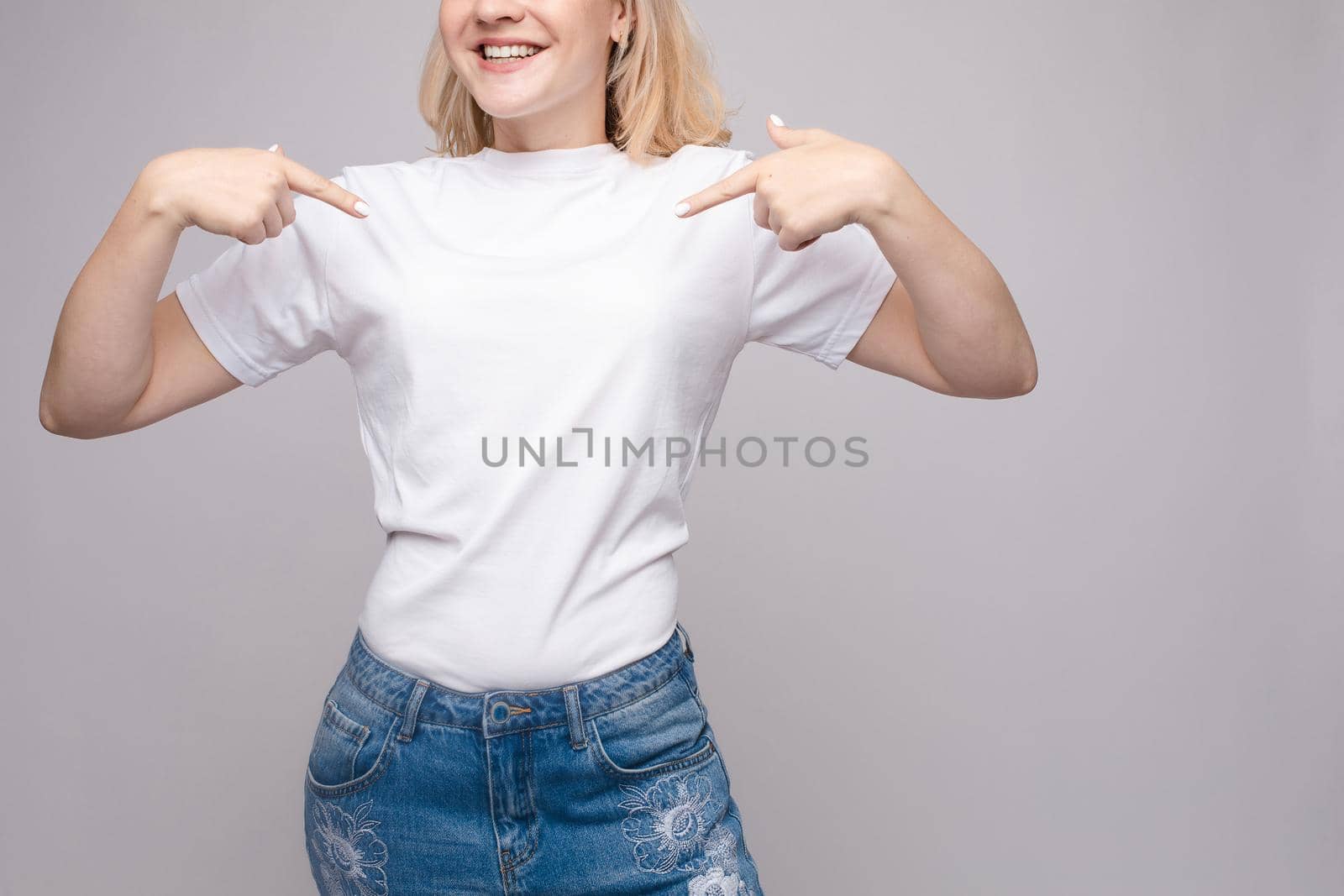 Cropped view of brunette standing in white shirt and jeans by StudioLucky