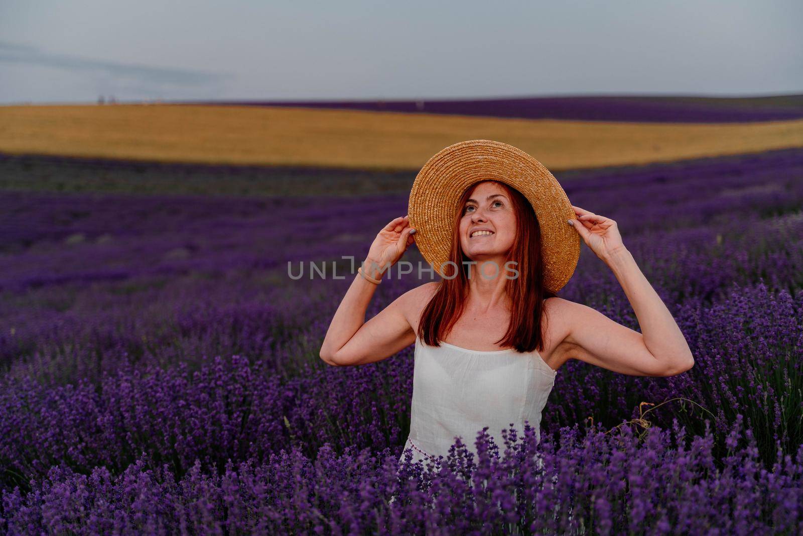 Close up portrait of a happy young woman in a dress on blooming fragrant lavender fields with endless rows. . Bushes of lavender purple fragrant flowers on lavender fields. by Matiunina