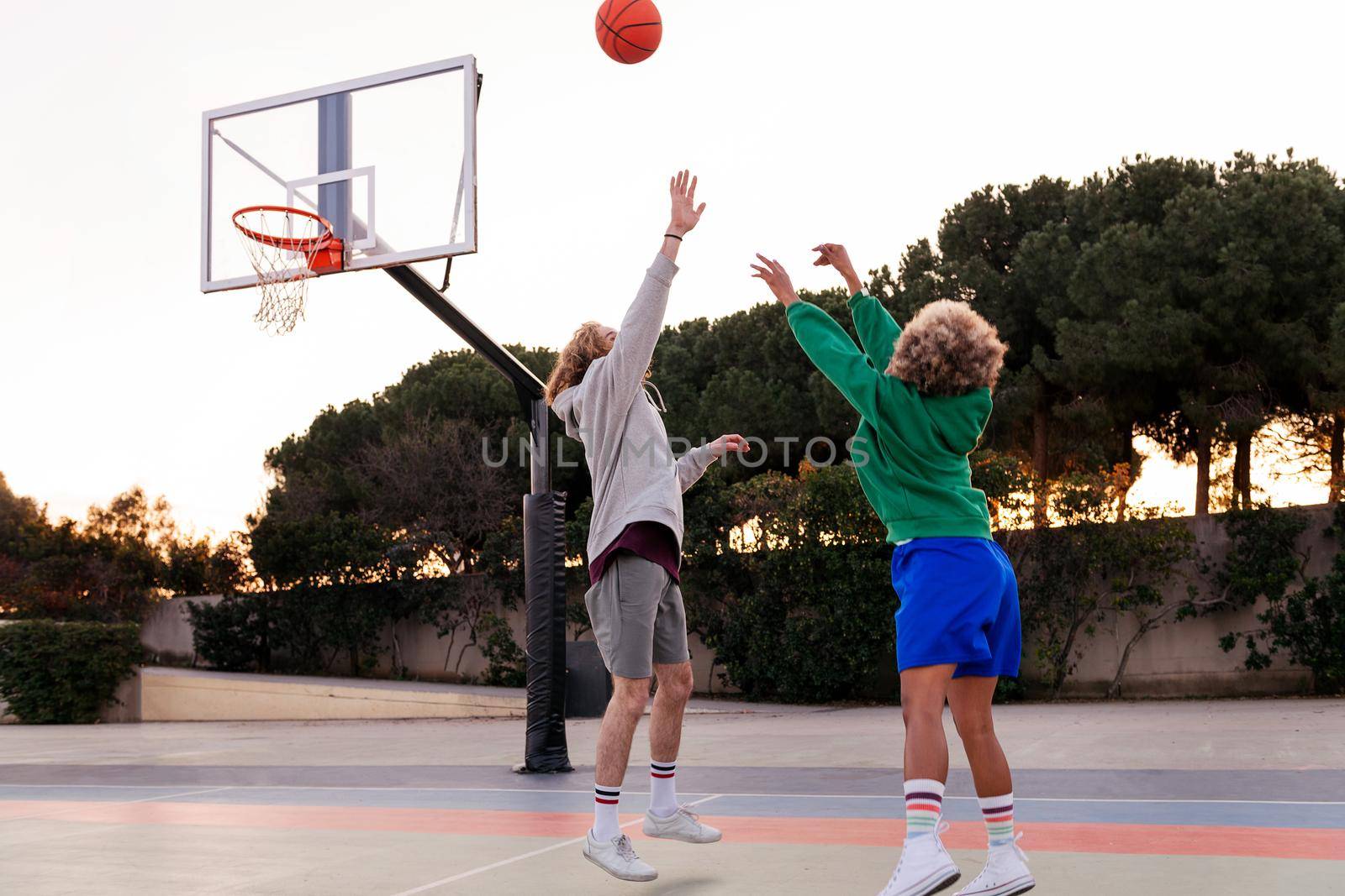 two young friends playing basketball on a city court, concept of urban sport in the street, copy space for text