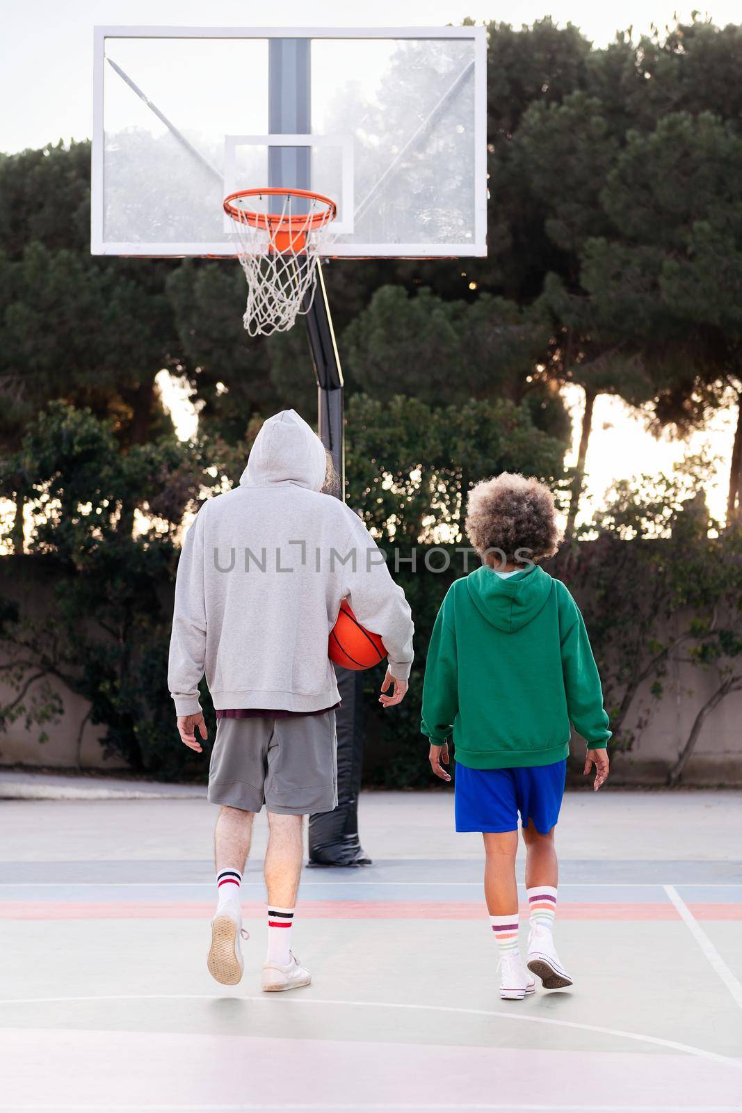 rear view of latin woman and caucasian man chatting walking down the court after basketball practice, concept of friendship and urban sport in the street, copy space for text