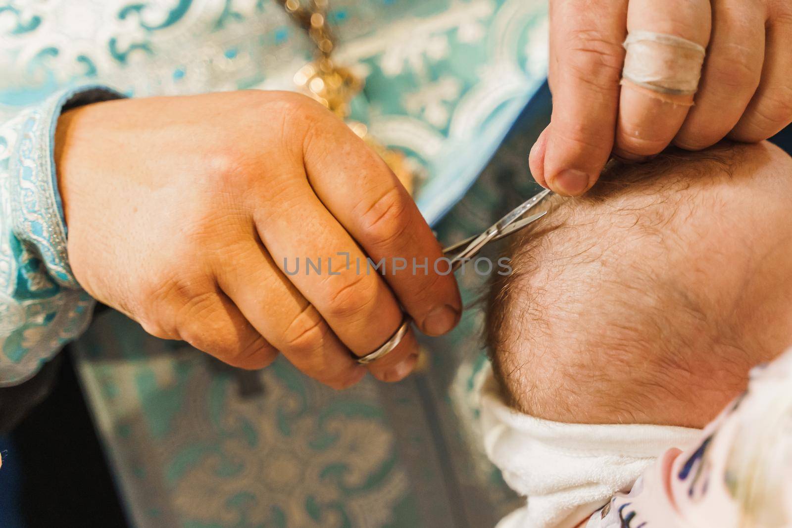 Hair cutting in a church for a year old child. Holy father cuts the hair of a baby. Orthodox tradition and faith. Equipment for praying. Pray for people life. Pray to god