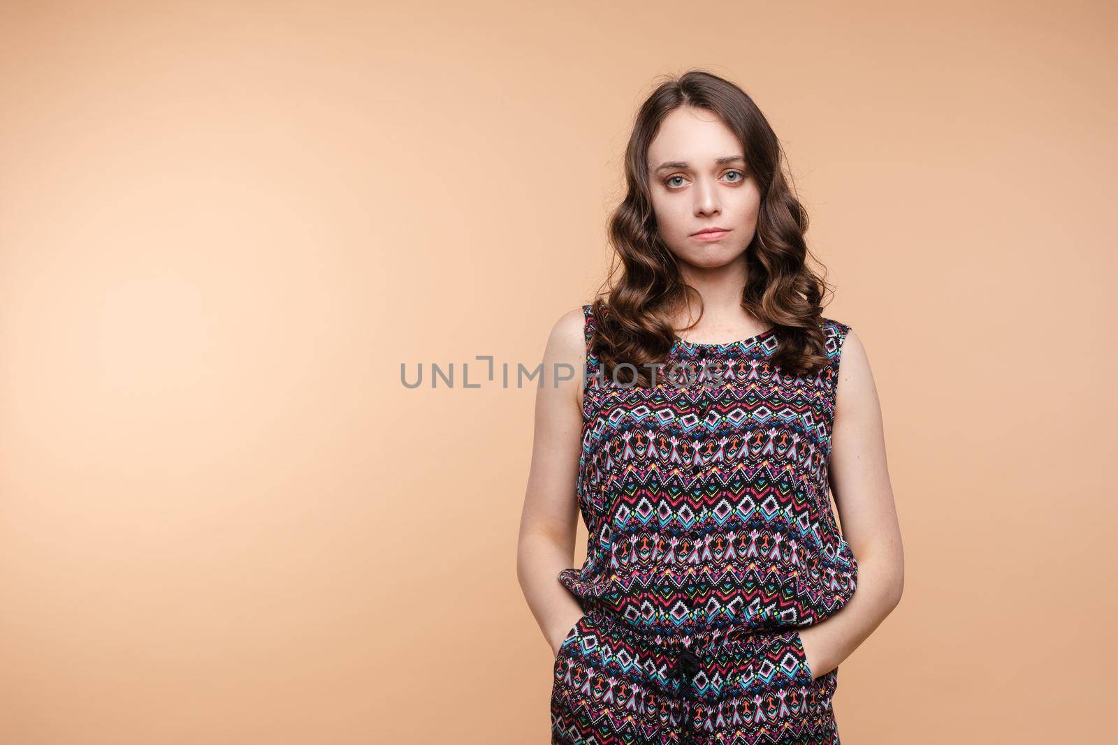 Upset young beautiful woman standing with crossed hands isolated at white studio background medium long shot. Unhappy European female looking down having negative emotion