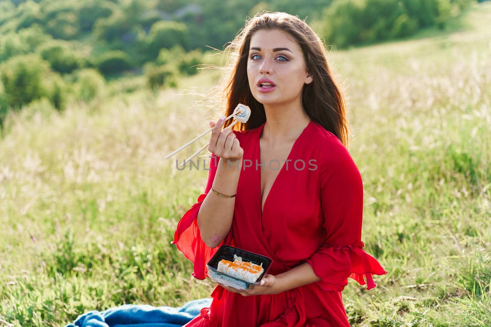 Sushi and sexy girl with blue eyes at picnic. Food delivery from japanese restaurant. Advert for social networks. Pretty girl eats sushi set in the park by Rabizo