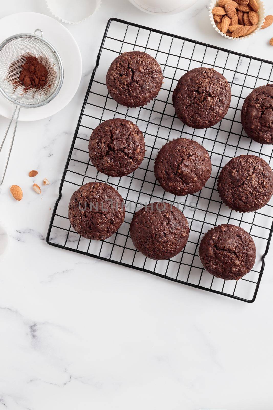 Freshly baked chocolate muffins on a grid on white table