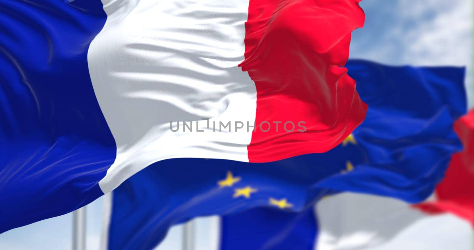 Detail of the national flag of France waving in the wind with blurred european union flag in the background on a clear day. Democracy and politics. European country. Selective focus.