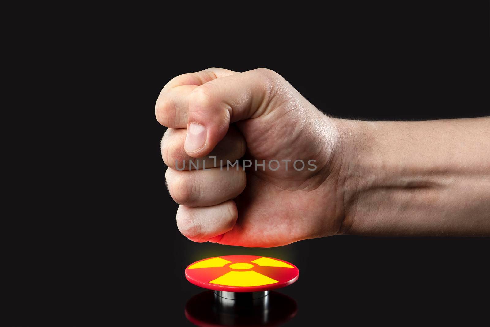 The hand presses the big red button. The concept of the threat of nuclear war. A threat to the world with a nuclear suitcase and a bomb. The hand presses the rocket launch button