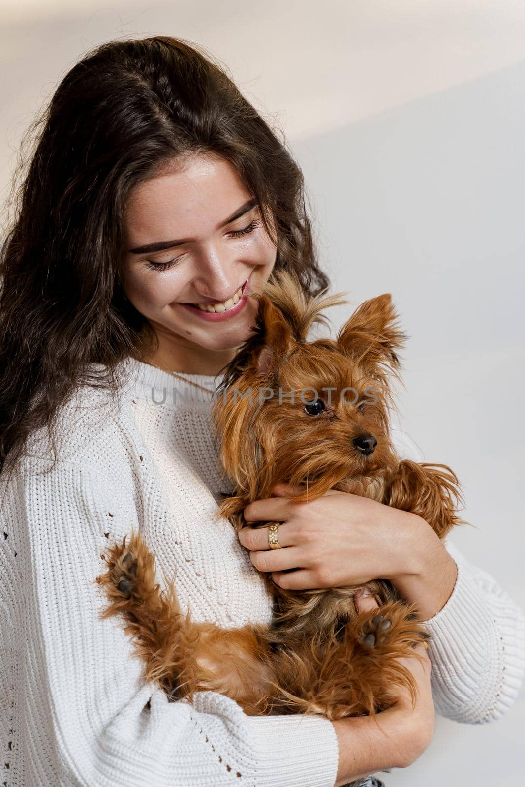 Girl holds brown dog isolated on white background. Young attractive woman with dog yorkshire terrier smiles. Close up photo. Pet care. People and pets by Rabizo
