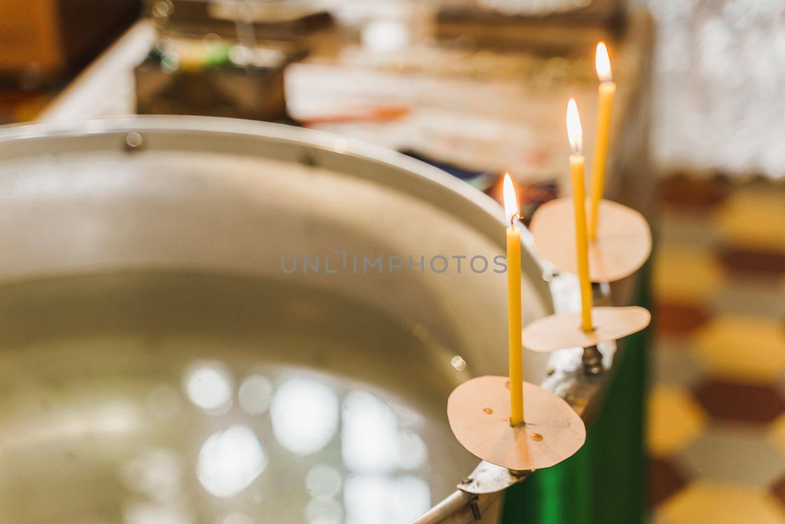 Font and 3 burning candles with water for baby in church for Epiphany. Prepearing for bathing for child in a baptistery