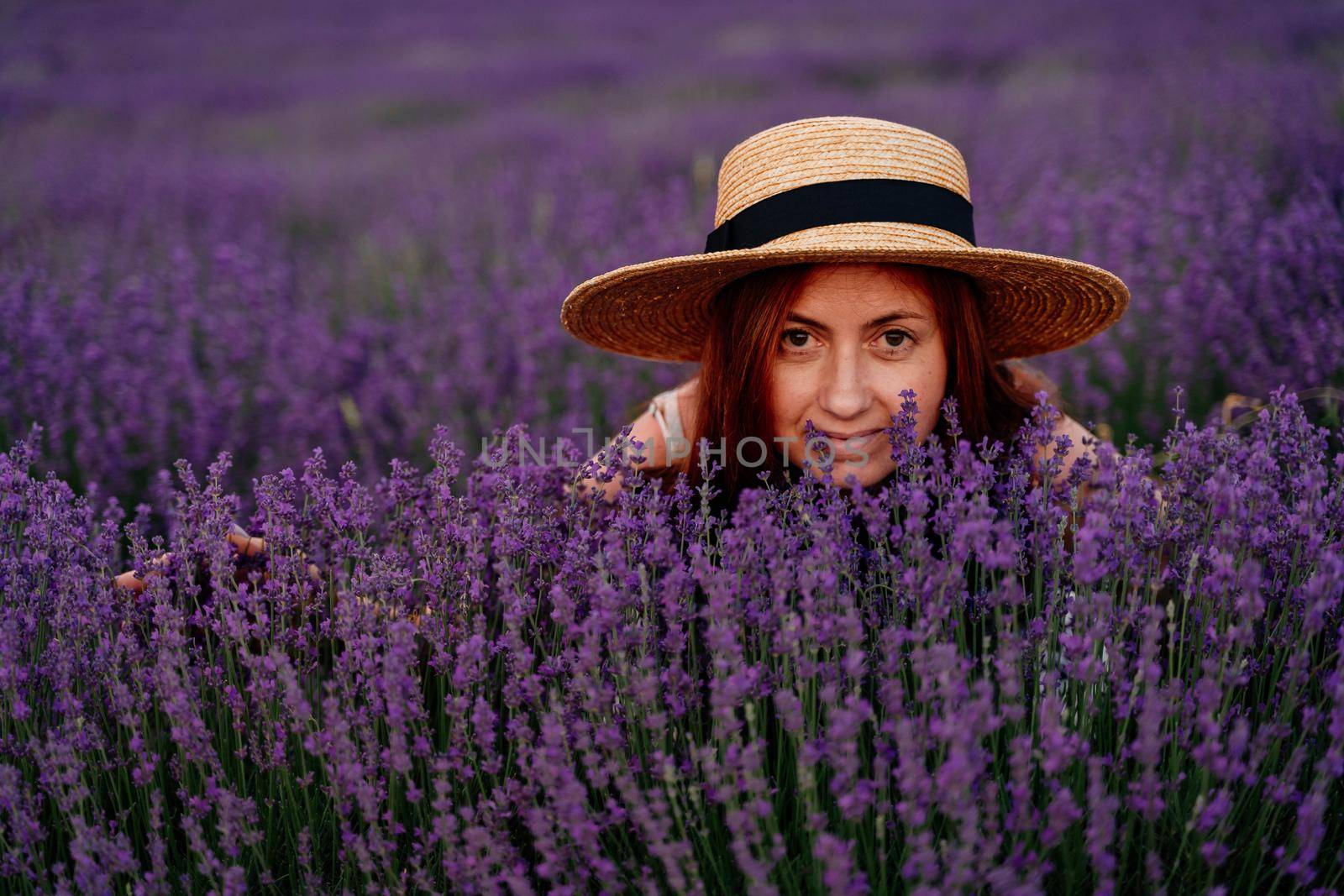 Close up portrait of a happy young woman in a dress on blooming fragrant lavender fields with endless rows. . Bushes of lavender purple fragrant flowers on lavender fields. by Matiunina