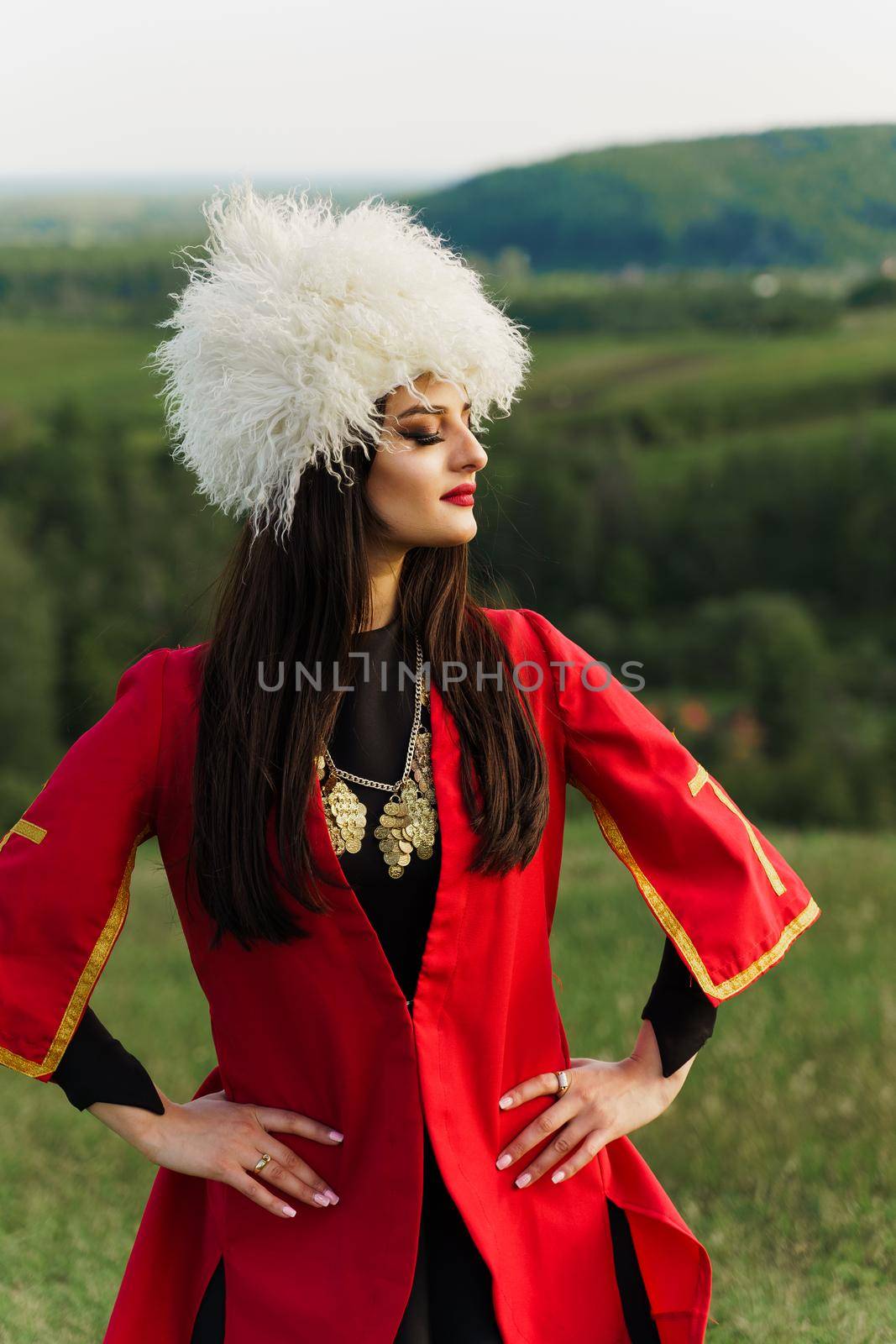 Georgian girl in papakha and red national dress with cross symbols. Attractive woman on the lake. Georgian culture lifestyle. Woman looks right side