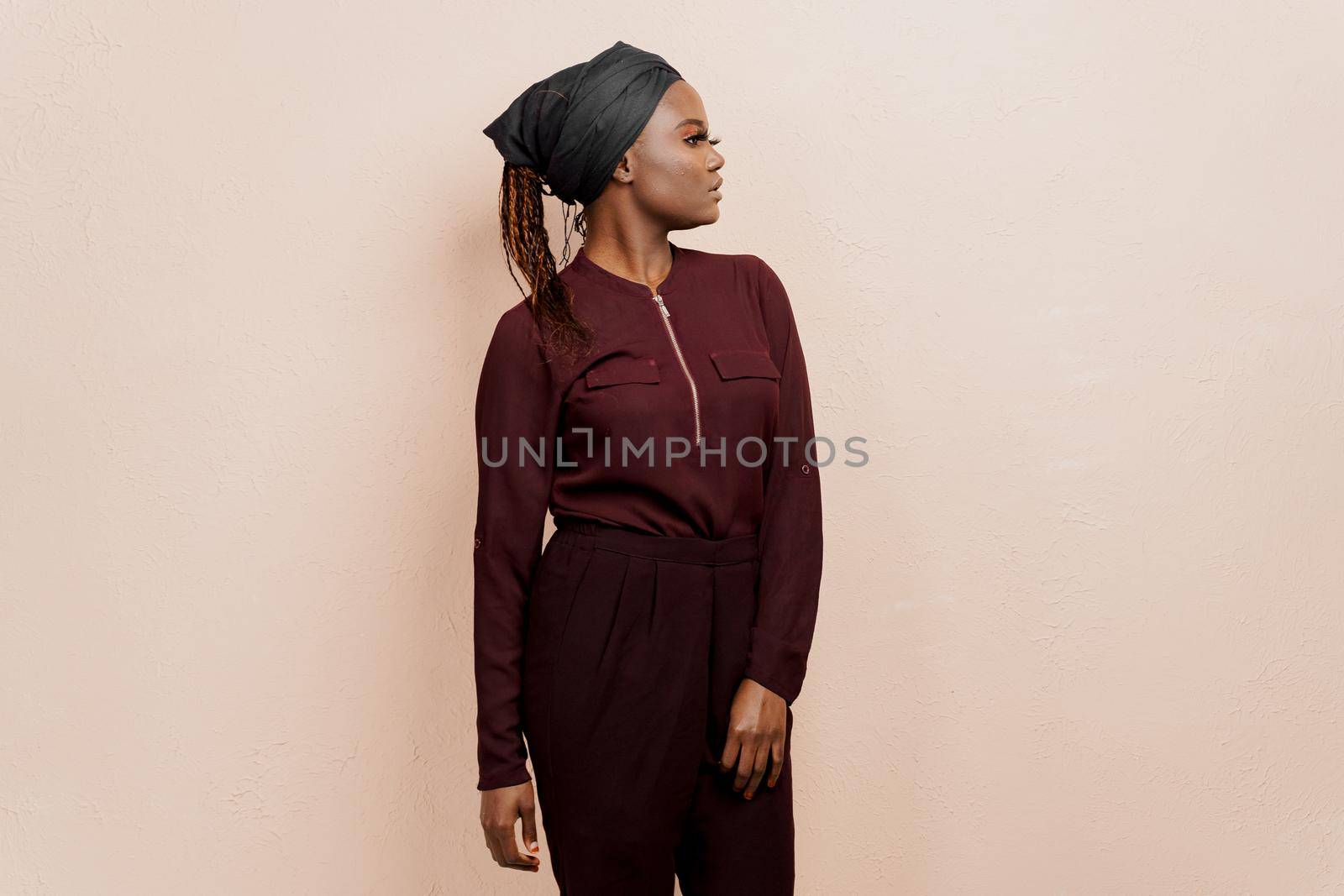 Muslim black girl looks right side. African woman weared in national dress and scarf isolated on peach background. by Rabizo