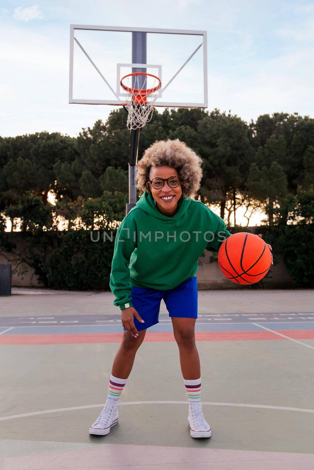 smiling latin woman playing on the basketball court in a city park, concept of urban sport in the street, copy space for text