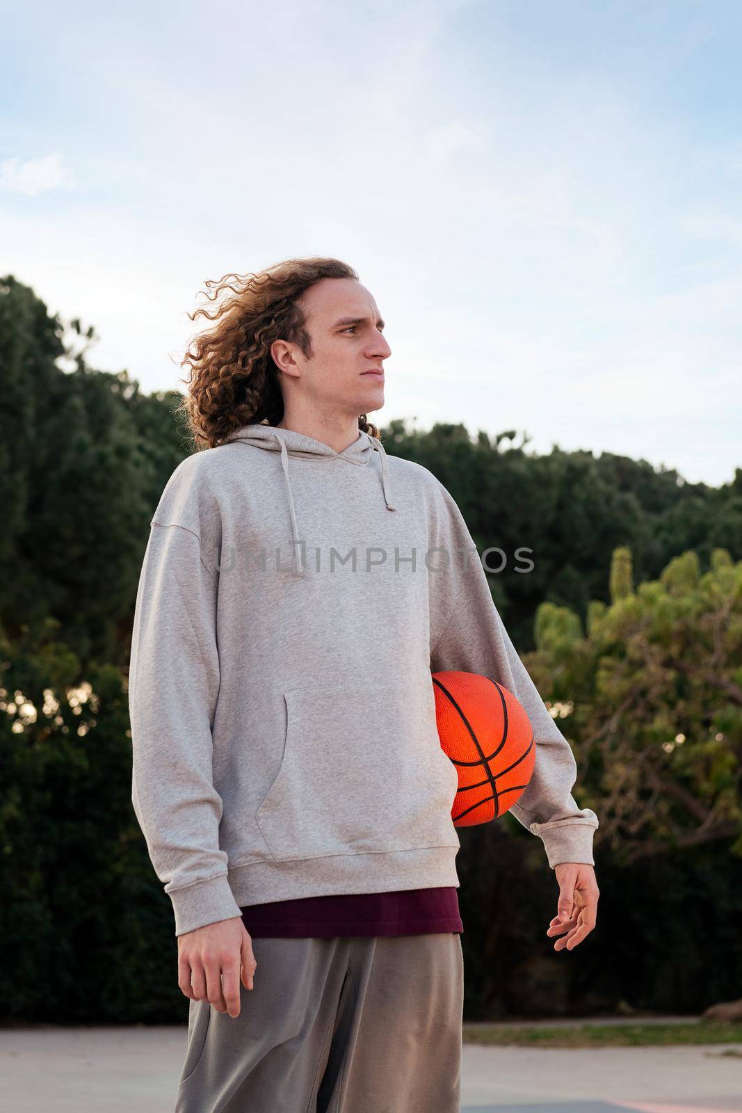 caucasian man outdoors with a basketball under his arm, concept of urban sport in the street, copy space for text