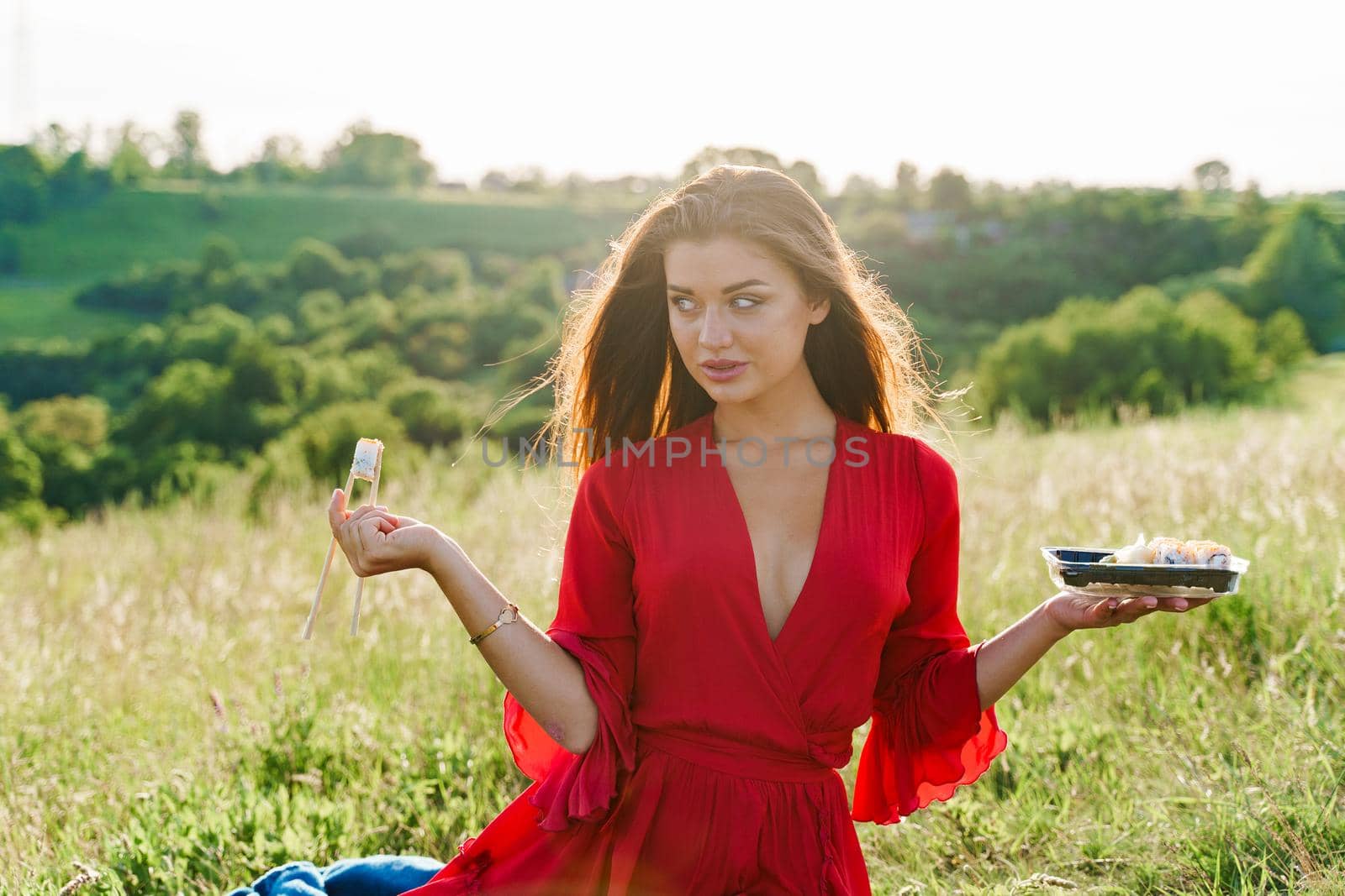 Sushi and sexy girl with blue eyes at picnic. Food delivery from japanese restaurant. Advert for social networks. Pretty girl with sushi set in 2 hand in the park by Rabizo