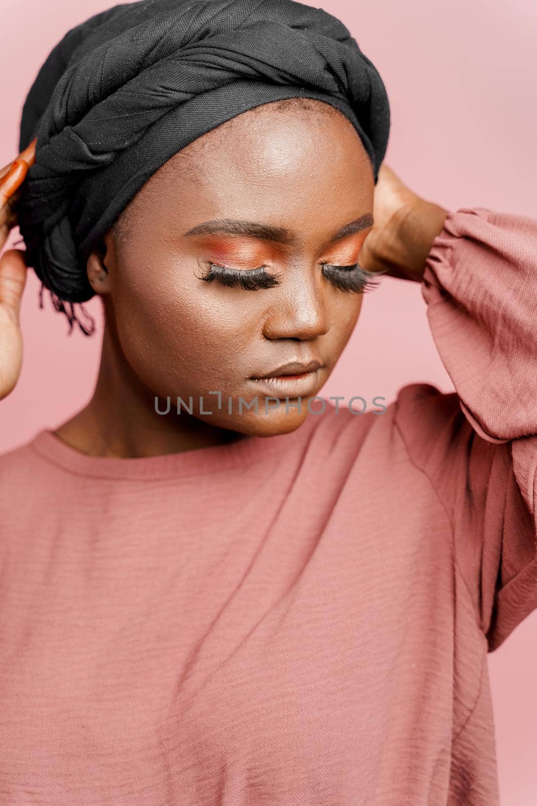 Muslim woman with closed eyes close-up. Relax and meditation. African black attractive girl vertical portrait isolated on pink background. by Rabizo