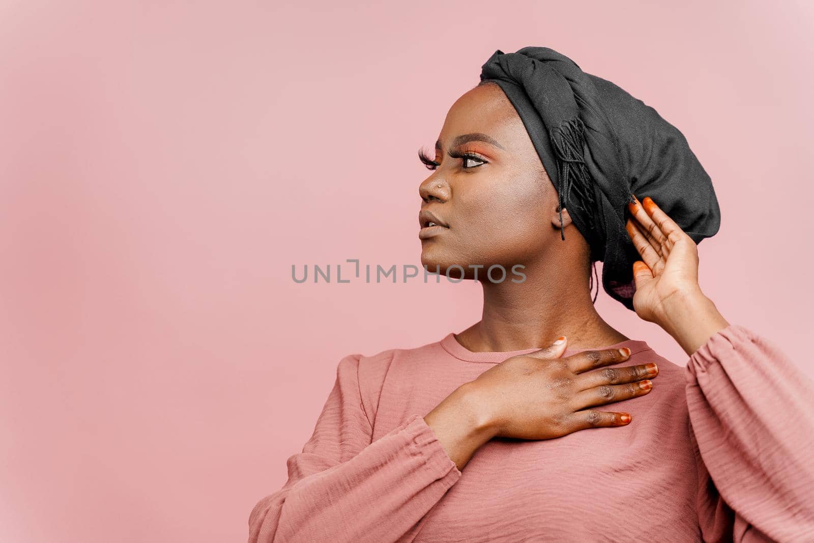 Muslim woman with closed eyes close-up. Relax and meditation. African black attractive girl portrait isolated on pink background. by Rabizo