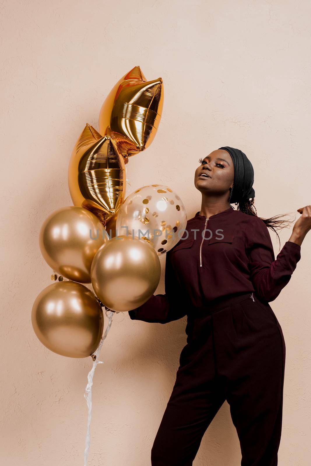 Eid al-Adha celebration. Muslim national holiday. Attractive girl with golden helium balloons isolated peach background. by Rabizo