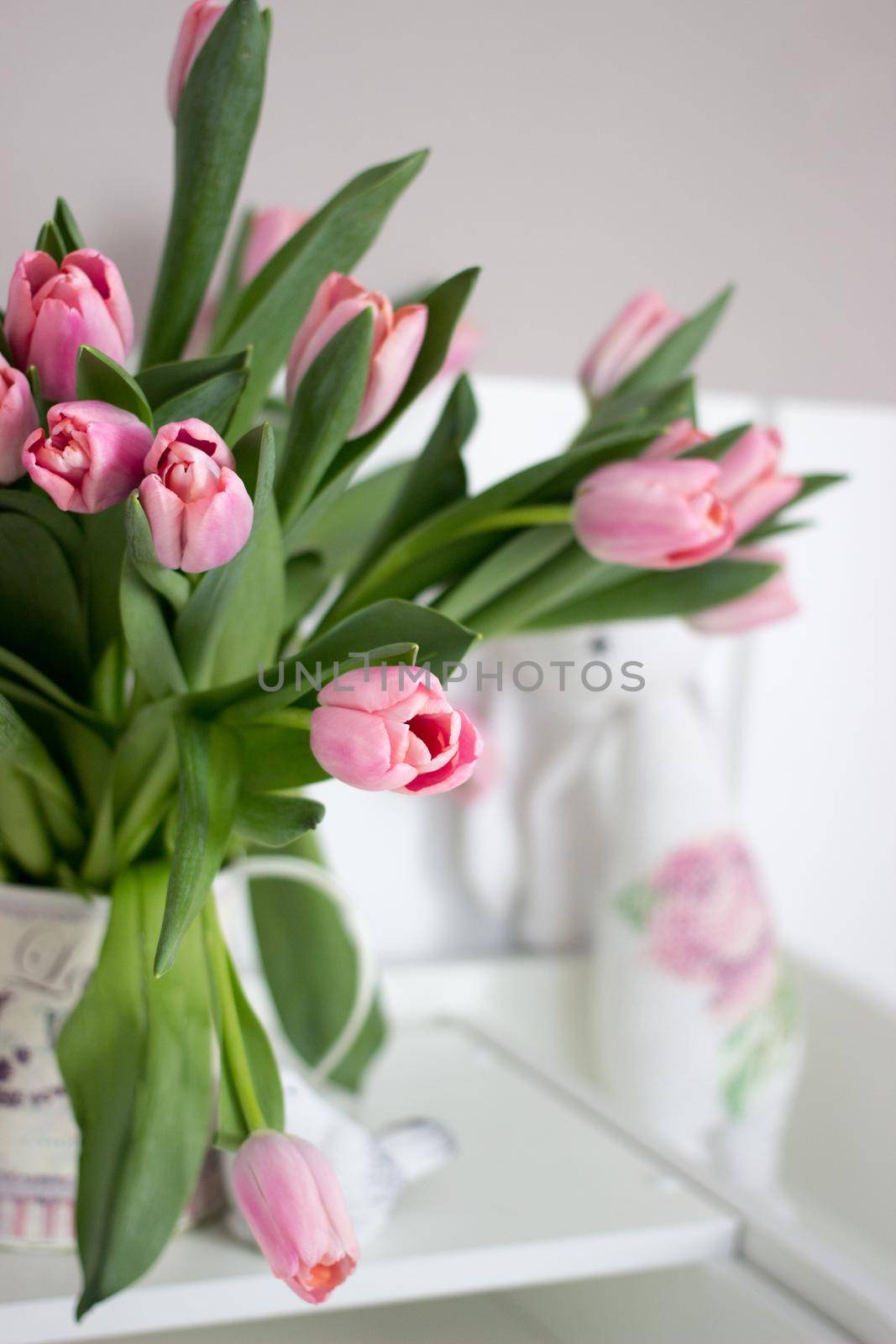 Fresh pink tulip flowers bouquet on shelf in front of stone wall. View with copy space.