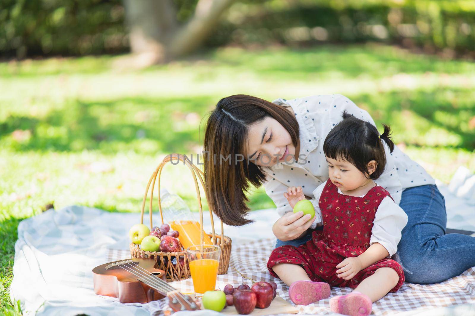 Family with children enjoying picnic in spring garden. Parents and kids having fun eating lunch outdoors in summer park.