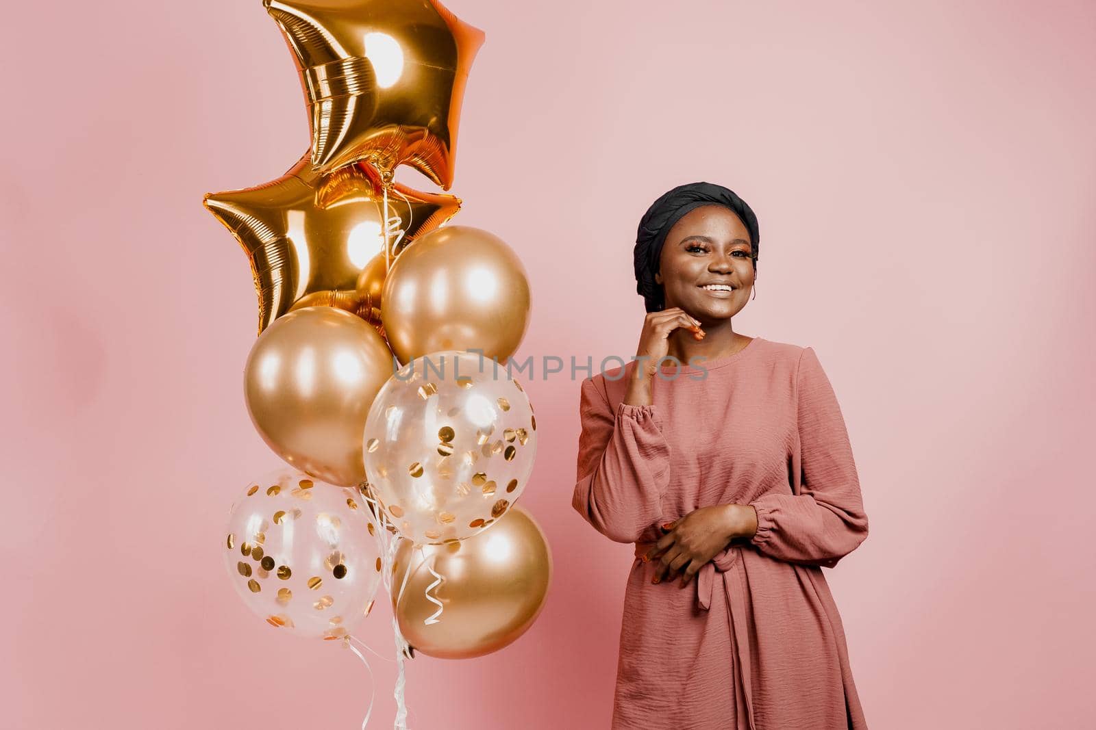 Muslim new year party with golden balloons for black woman. African attractive girl celebration of the end of year. Happy emotion. by Rabizo