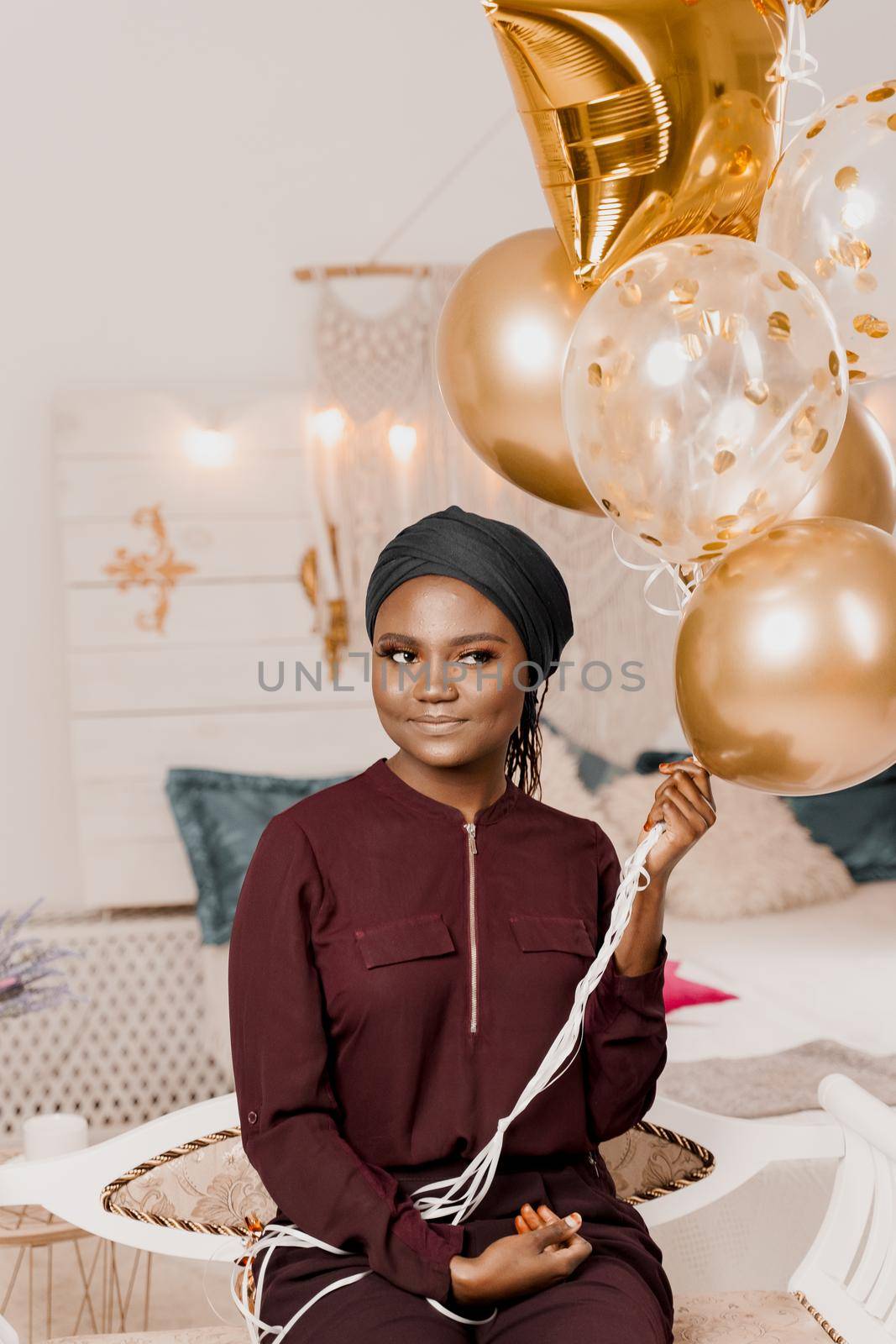 Christmas celebration. African american holiday. Attractive girl with golden helium balloons isolated peach background