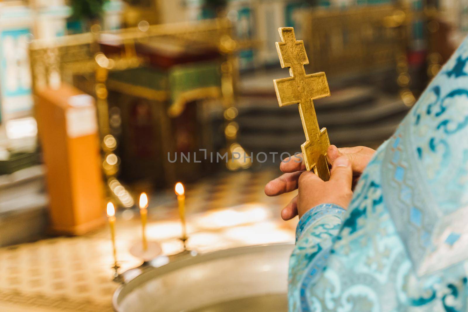 Holy father near babtistery in his robe with a golden cross in his hands in church. Orthodox tradition and faith. Equipment for praying