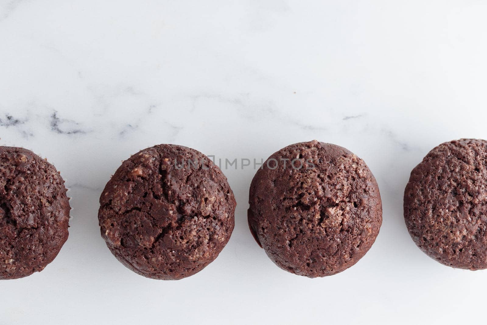 The row of chocolate muffins on a white marble table