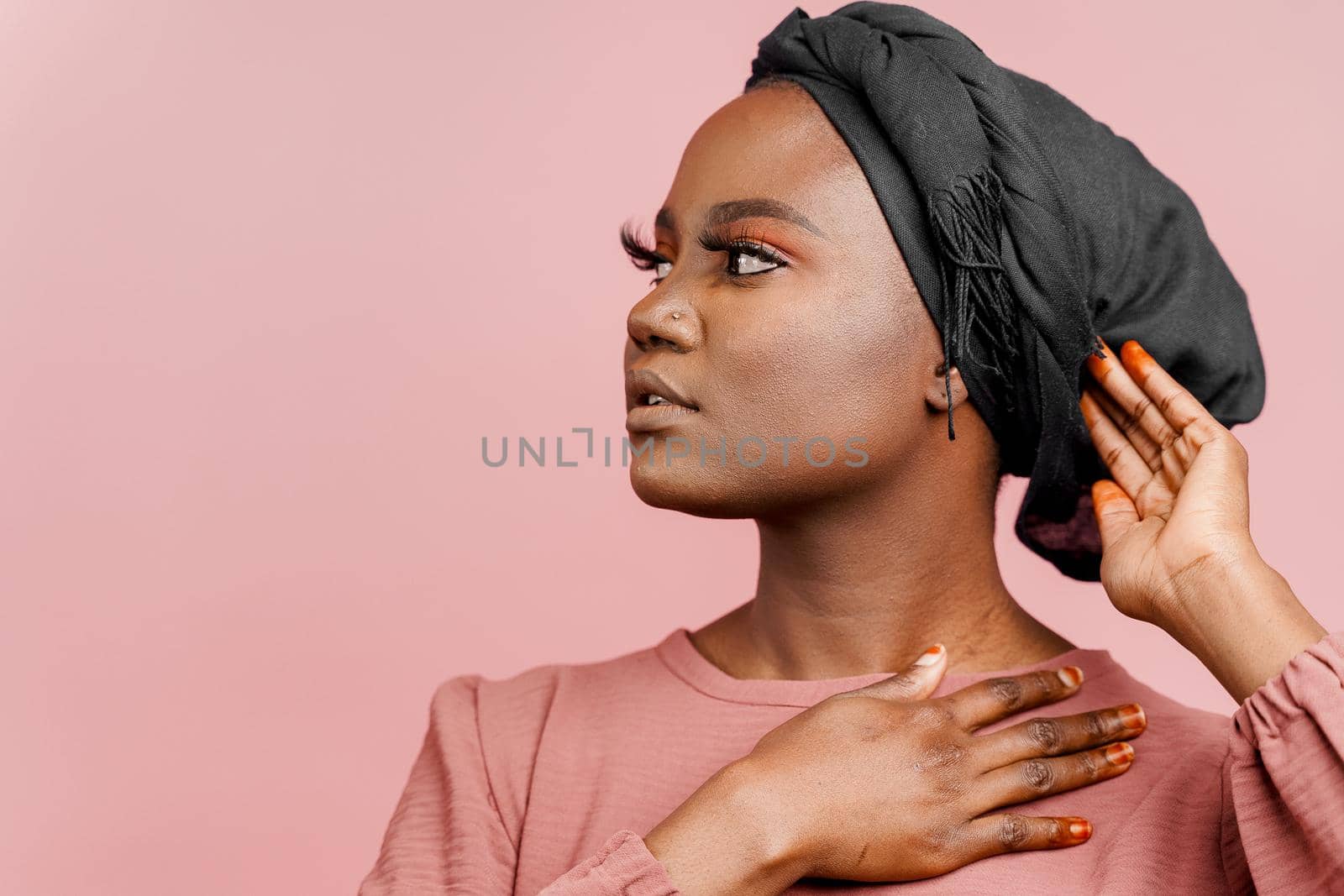 Muslim woman with closed eyes close-up. Relax and meditation. African black attractive girl portrait isolated on pink background. by Rabizo