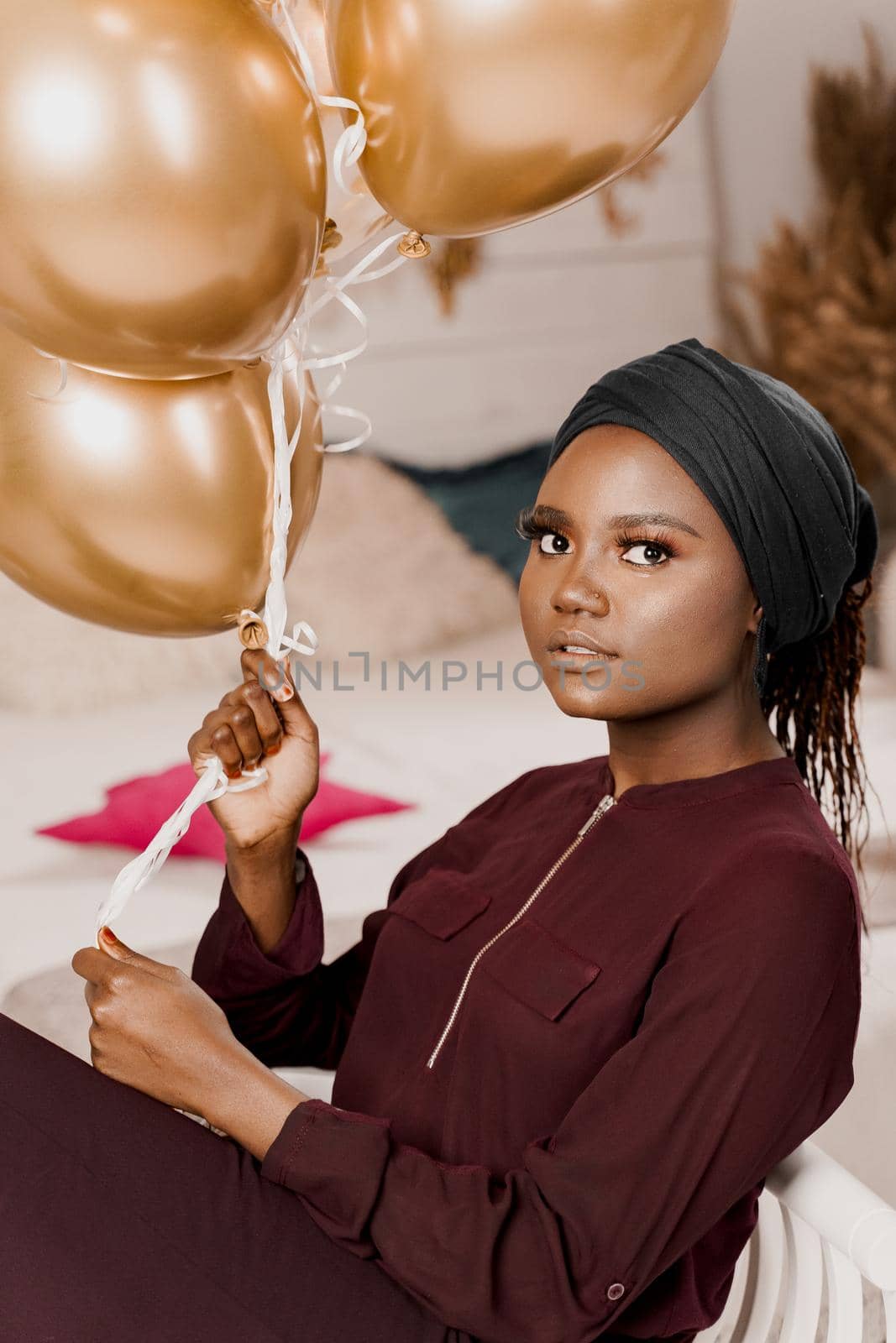 Black girl with golden ballons have a party and smiles. African woman celebrate graduation. Happy emotions of muslim young woman