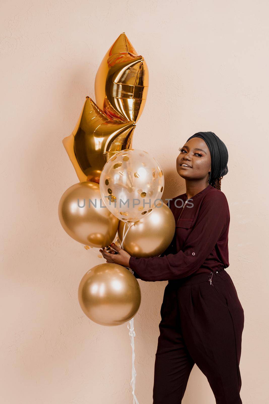 Muslim new year party with golden balloons for black woman. African attractive girl celebration of the end of year. Happy emotion. by Rabizo