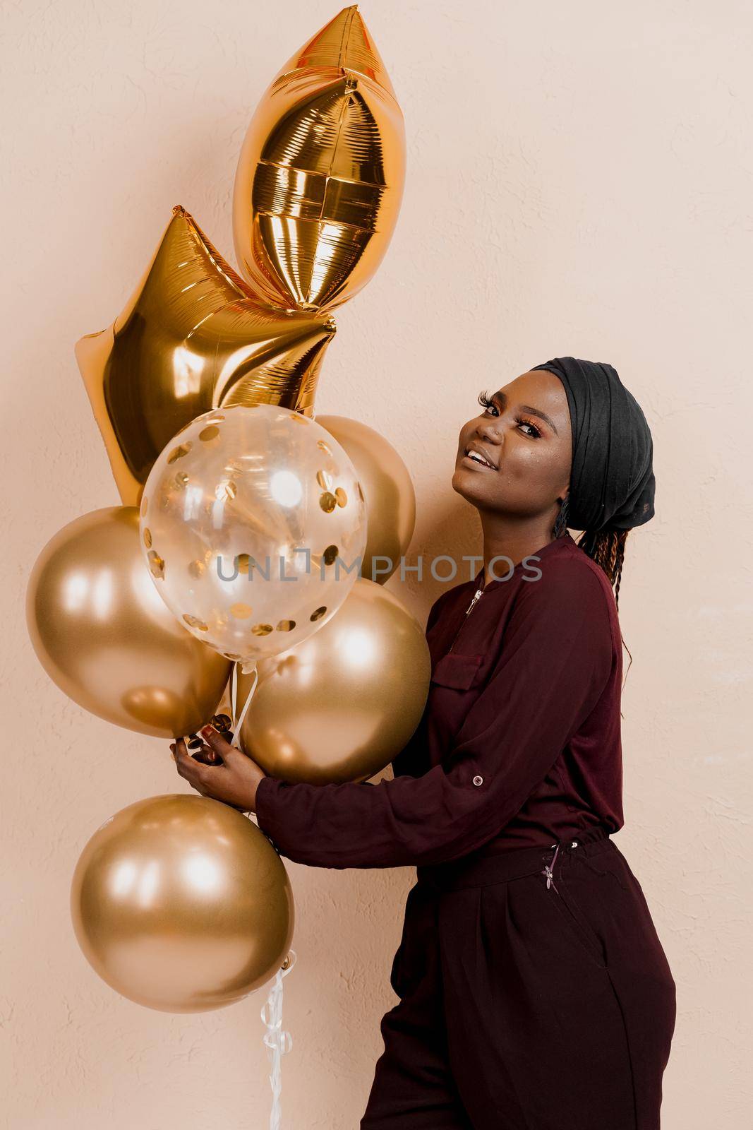 Eid al-Adha celebration. Muslim national holiday. Attractive girl with golden helium balloons isolated peach background