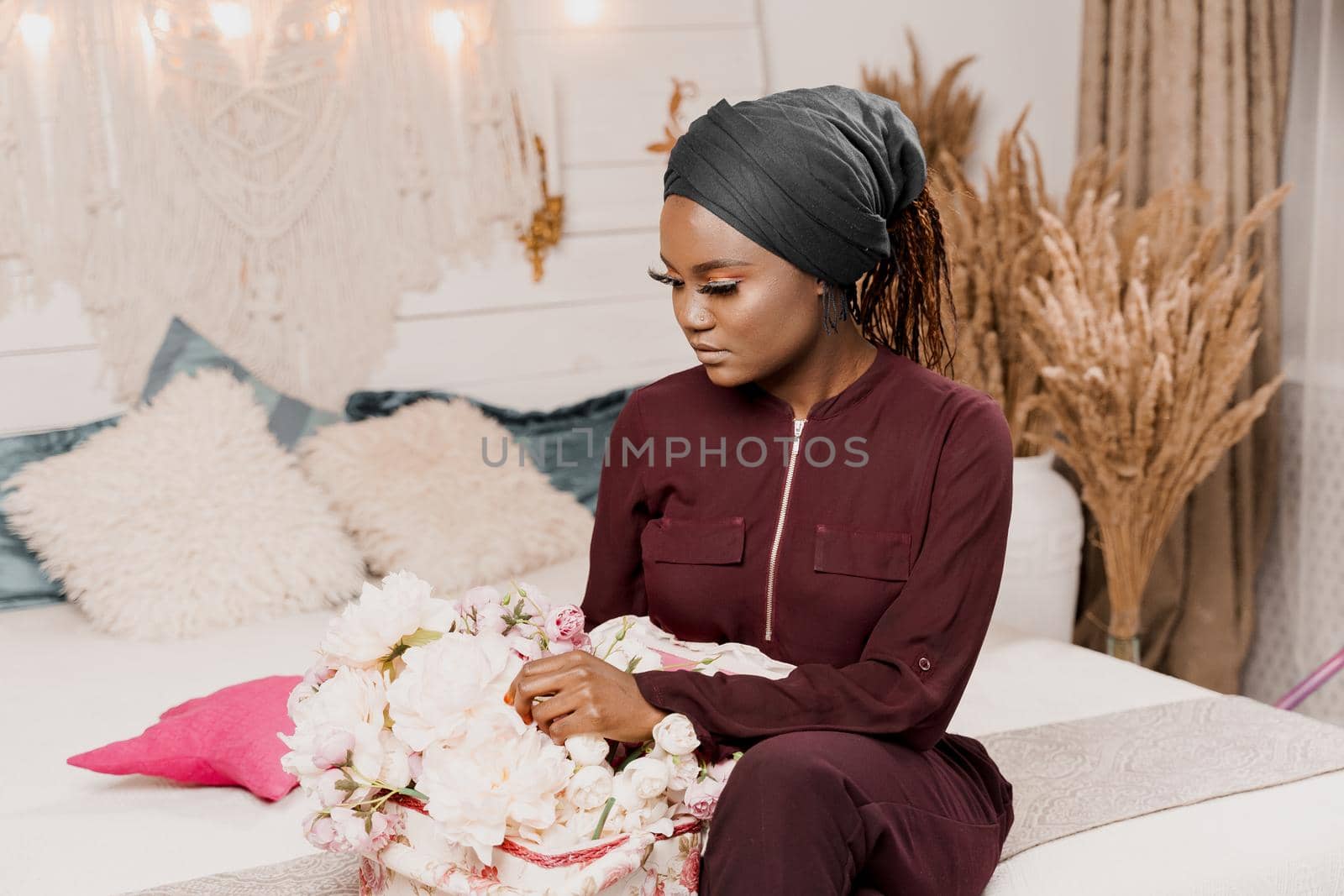 Muslim girl with flowers seats and looks at bouquet. African young woman with beautiful flowers from her boyfriend on the valentines day. Holiday celebration