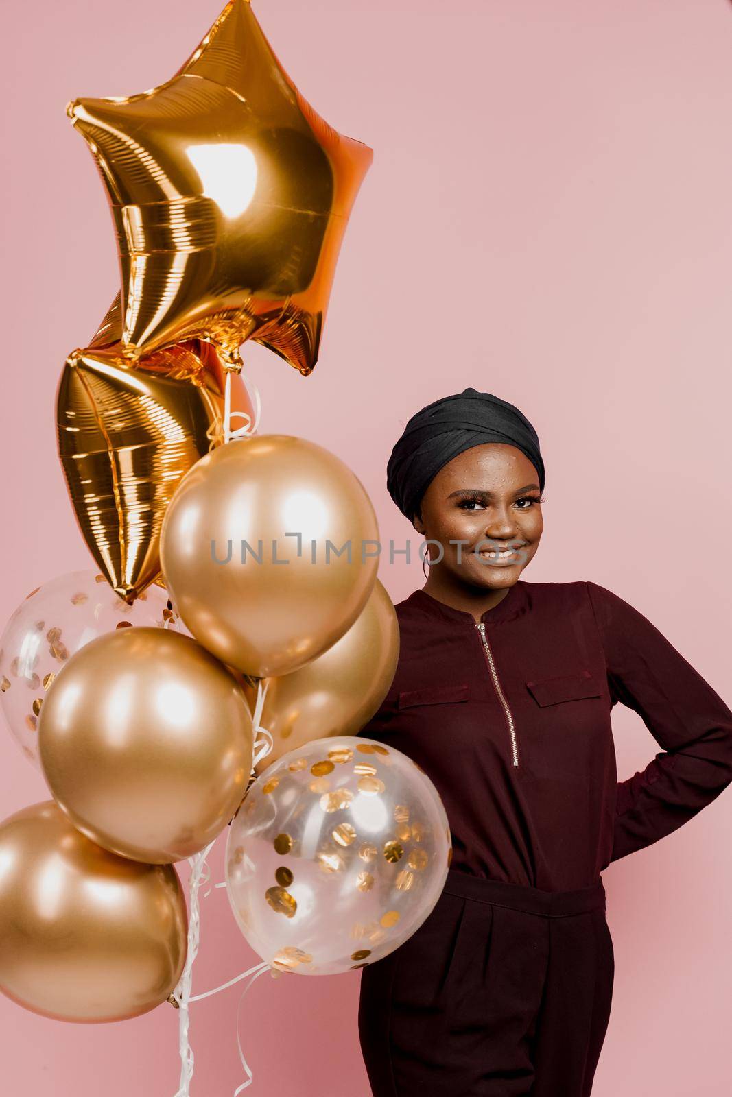 Christmas celebration. African american holiday. Attractive girl with golden helium balloons isolated peach background. by Rabizo