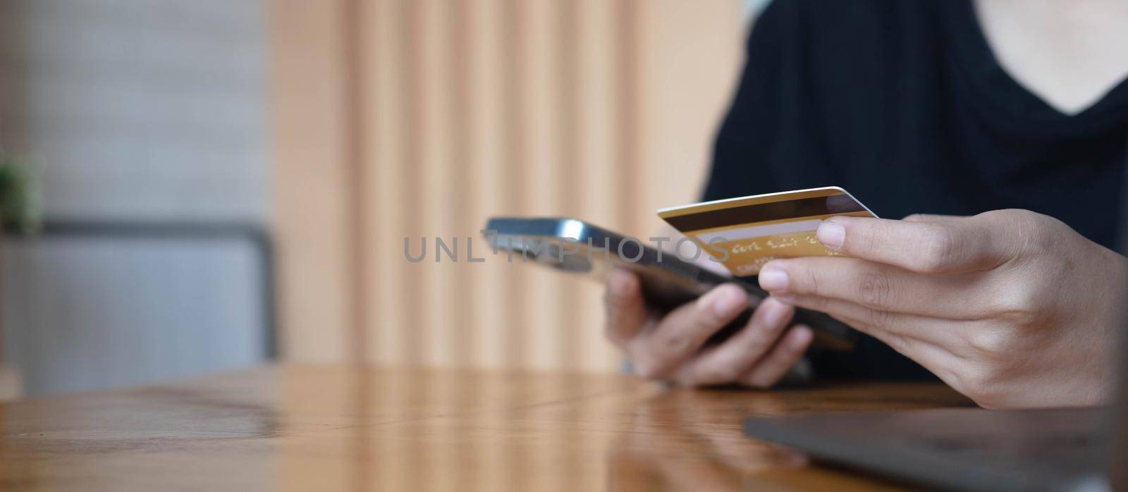 Close up woman hand using credit card and smartphone laptop for buying online shopping.