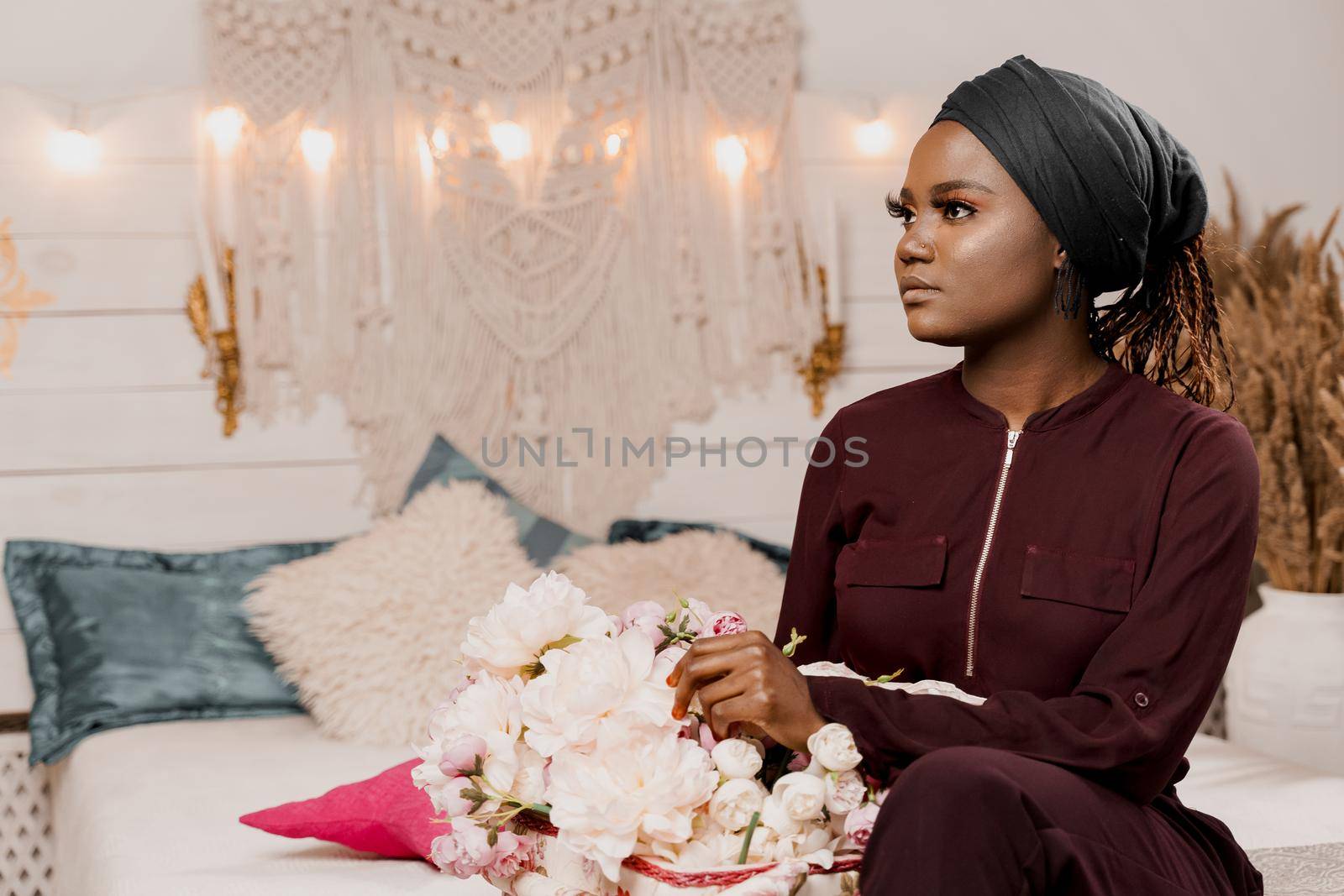 Muslim girl with flowers seats and looks left side African young woman with beautiful bouquet from her boyfriend on the valentines day. Holiday celebration. by Rabizo