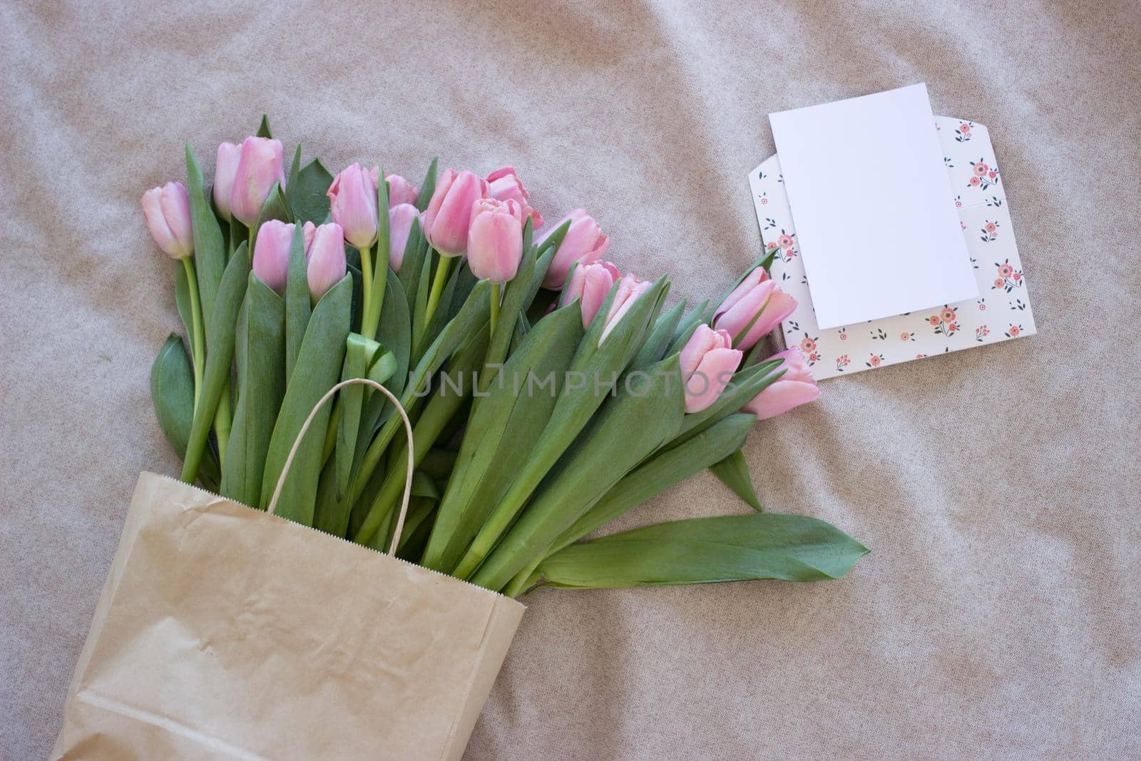 Fresh pink tulip flowers in paper bag on light background. Top view with copy space by KatrinBaidimirova