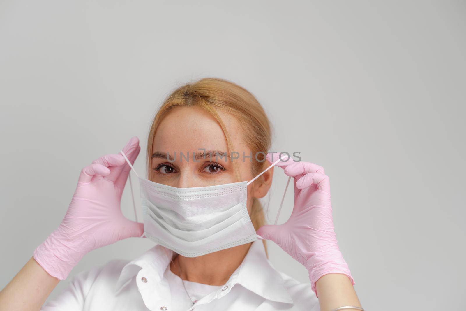 The doctor puts on a mask. Close-up portrait of medical staff. A woman in a protective mask .Isolated on a white background. Healthcare, cosmetology and medical concept.